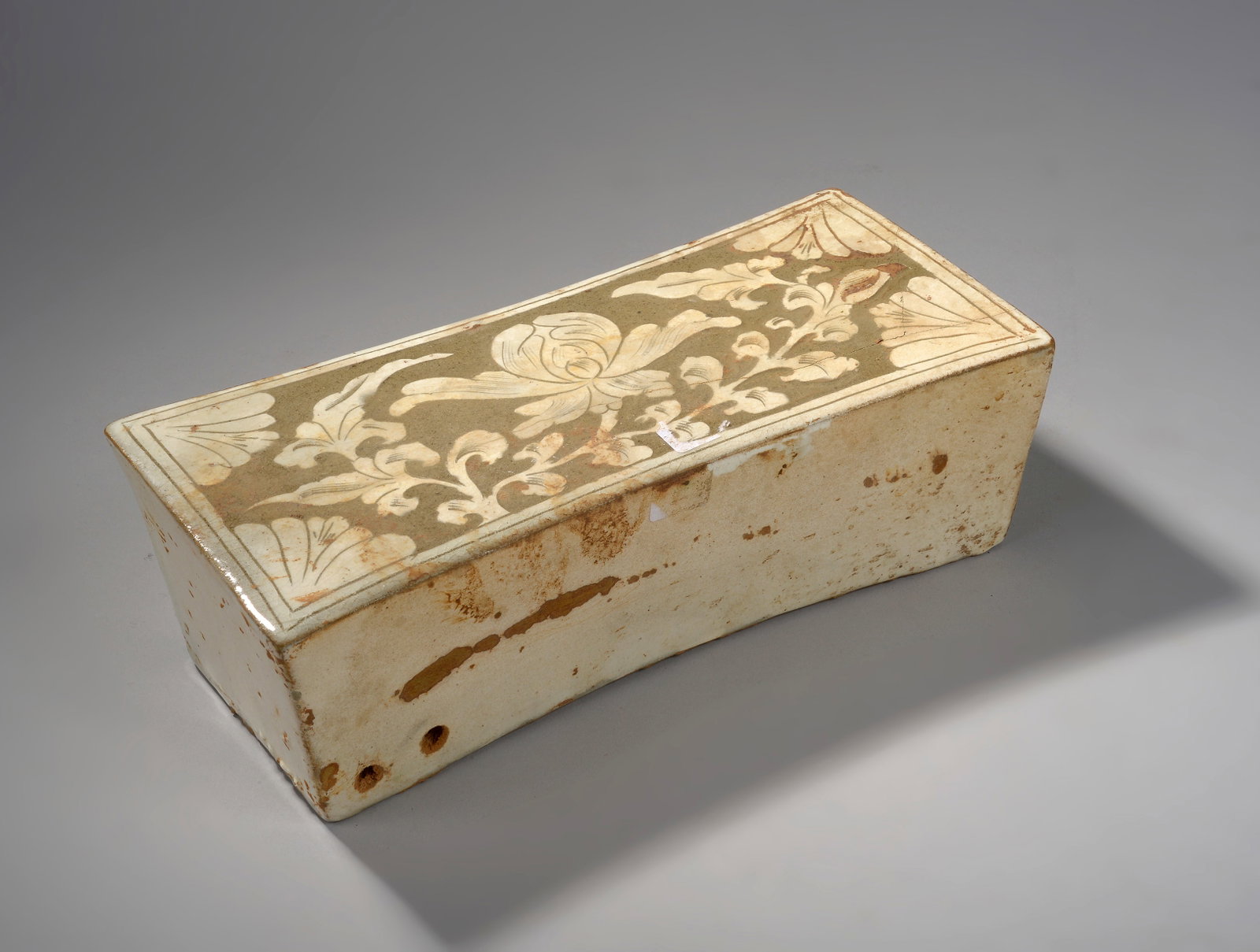 A quadrangular cizhu headrest made of porcelain stoneware, incised in cream glaze on a gray (1 of 2)