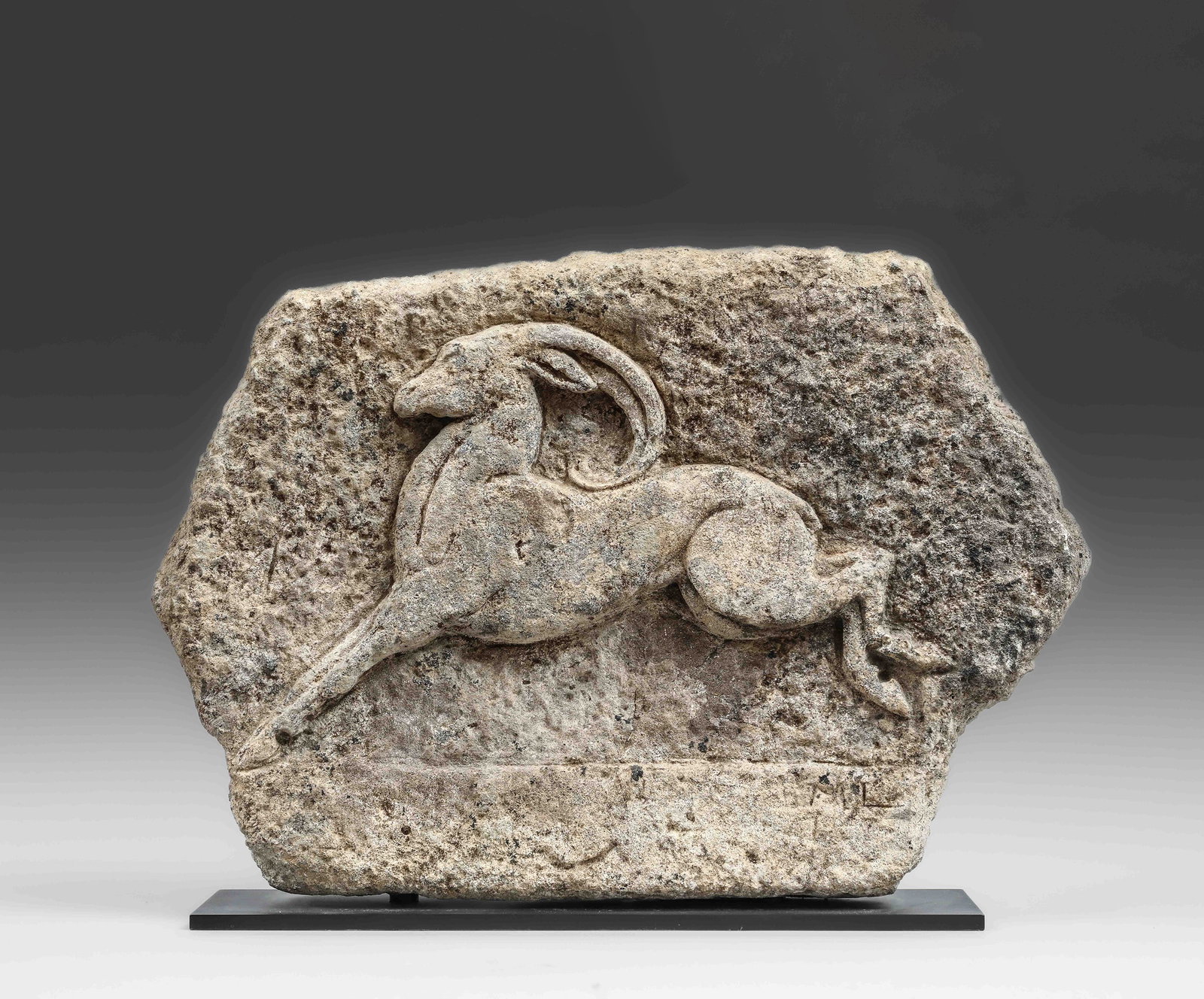 Archaic high relief, possibly Greek or Roman, chiseled in stone with a leaping ram or ibex motif.: Good condition, date to be determined. 50x35cm. Lot in international warehouse (outside the EU). For shipments to the European Union, import duties and/or taxes will apply and are the responsibility o