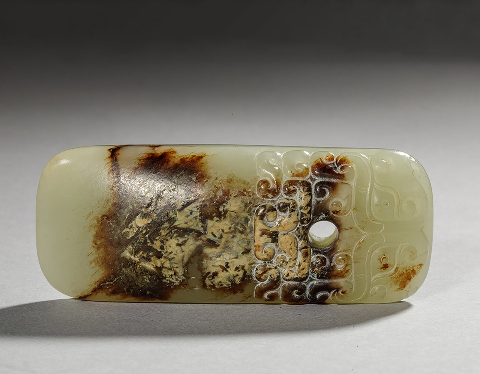 Important ceremonial dagger "Ge". Pale celadon green jade - Western Han Dynasty (Western Han period): Straight in shape with rounded corners, separated into two parts, smooth, tapered blade and pommel chiseled with Leïwen scrolls and a clearly defined Tao-Tie mask on both sides, pierced with susp