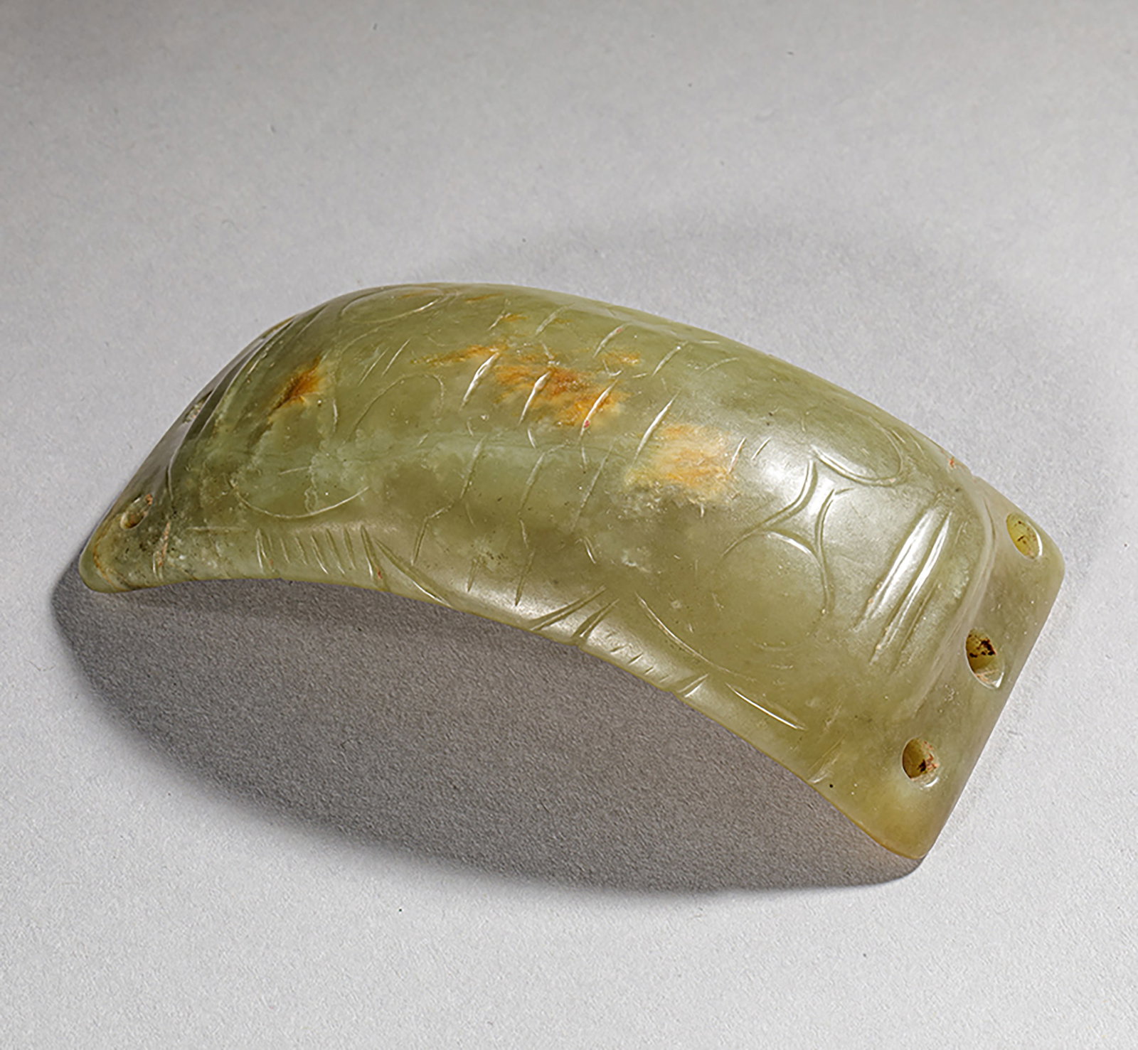 Archaic Chinese green and honey-colored jade ornament. China, Shang Dynasty, 6th to 9th century BC.: With three holes at each end and chiseled at the top. Green and honey jade. China Shang Dynasty 6th to 9th century BC. 9.5 x 4.9 cm. Lot in international warehouse (outside the EU). For shipments to t