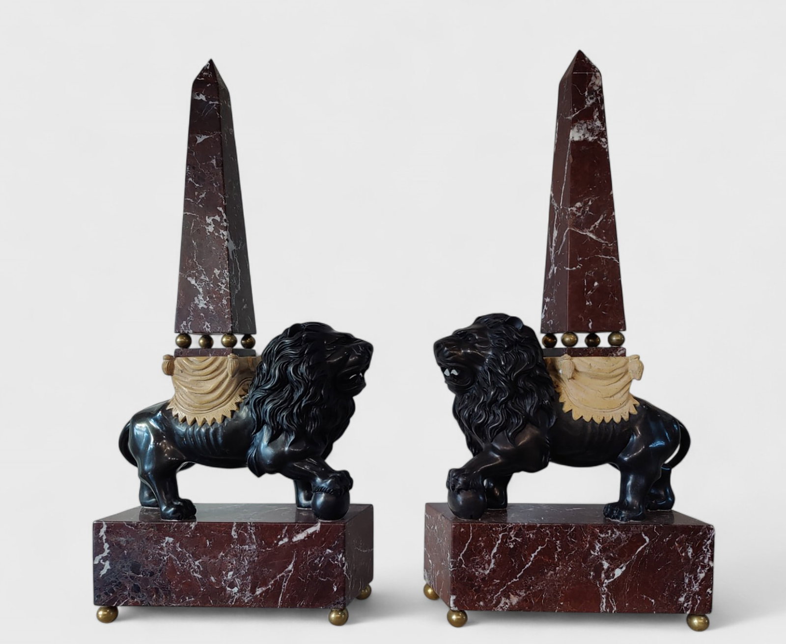 Pair of red marble obelisks on patinated bronze lions, Italy: Magnificent sculptures with a base and obelisk in red French marble, lions in black Belgian marble, and details in Nembro giallo marble. Dimensions: 75 x 33 x 13 cm. Batch in international warehouse (