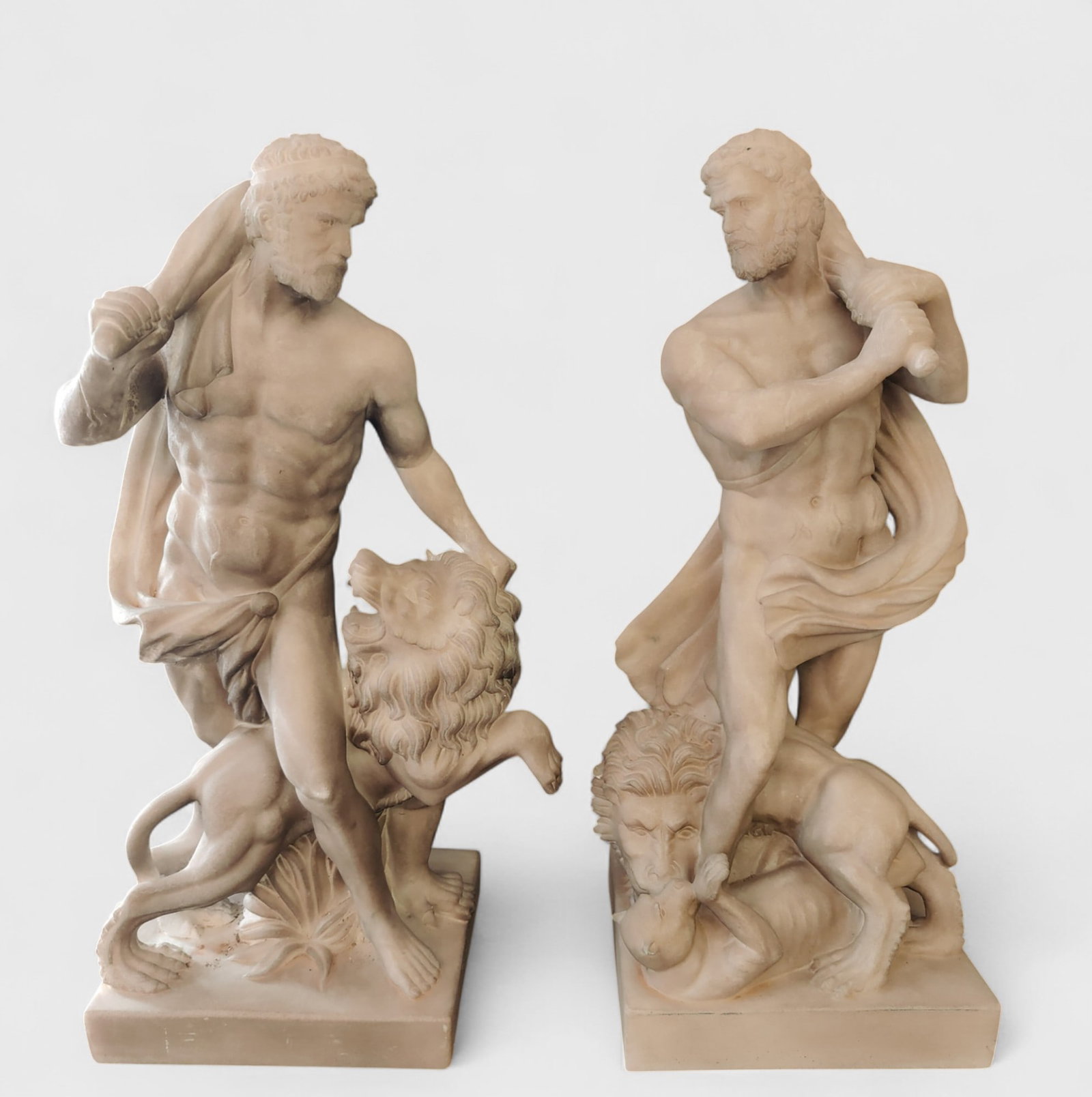 Pair of Hercules in Carrara marble with a scene subduing the lion, Italy: Carved white marble. Dimensions: 62 x 27 x 23 cm. Medium-sized and well-proportioned. The marble's beautiful patina and the carefully crafted figures stand out. Batch in international warehouse (withi