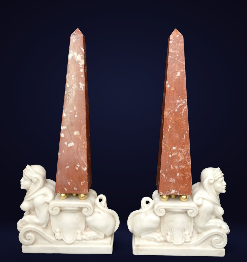 Pair of obelisks with sphinxes, Italy, 19th century: Pair of obelisks in red French marble, with a Carrara marble base and gilt bronze supports. Originally from a Venetian palace, they stand out for the sculpted sphinxes on the base, a rare and highly d