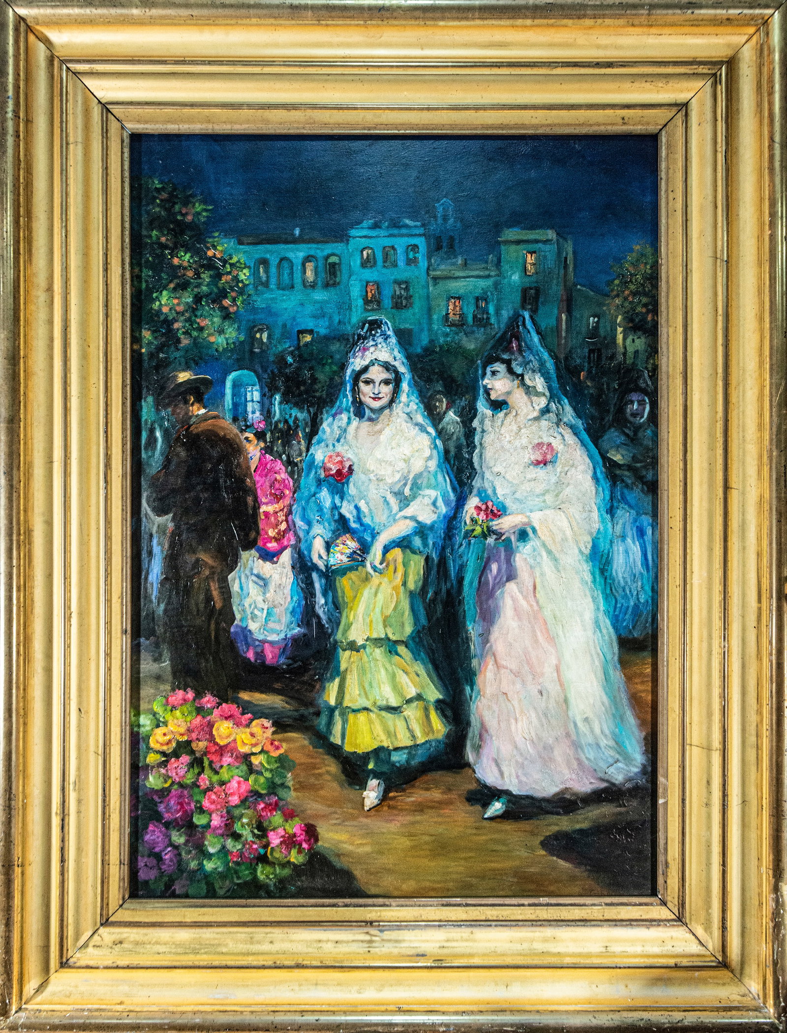 Gustavo Bacarisas (Gibraltar, 1873-1971) - The April Fair: Oil on canvas. Dimensions 127 x 90 / 157 x 118 cm. A nocturnal scene with an Andalusian flavor depicts two young women adorned with mantillas and flowers, moving through a festive street or plaza atmo