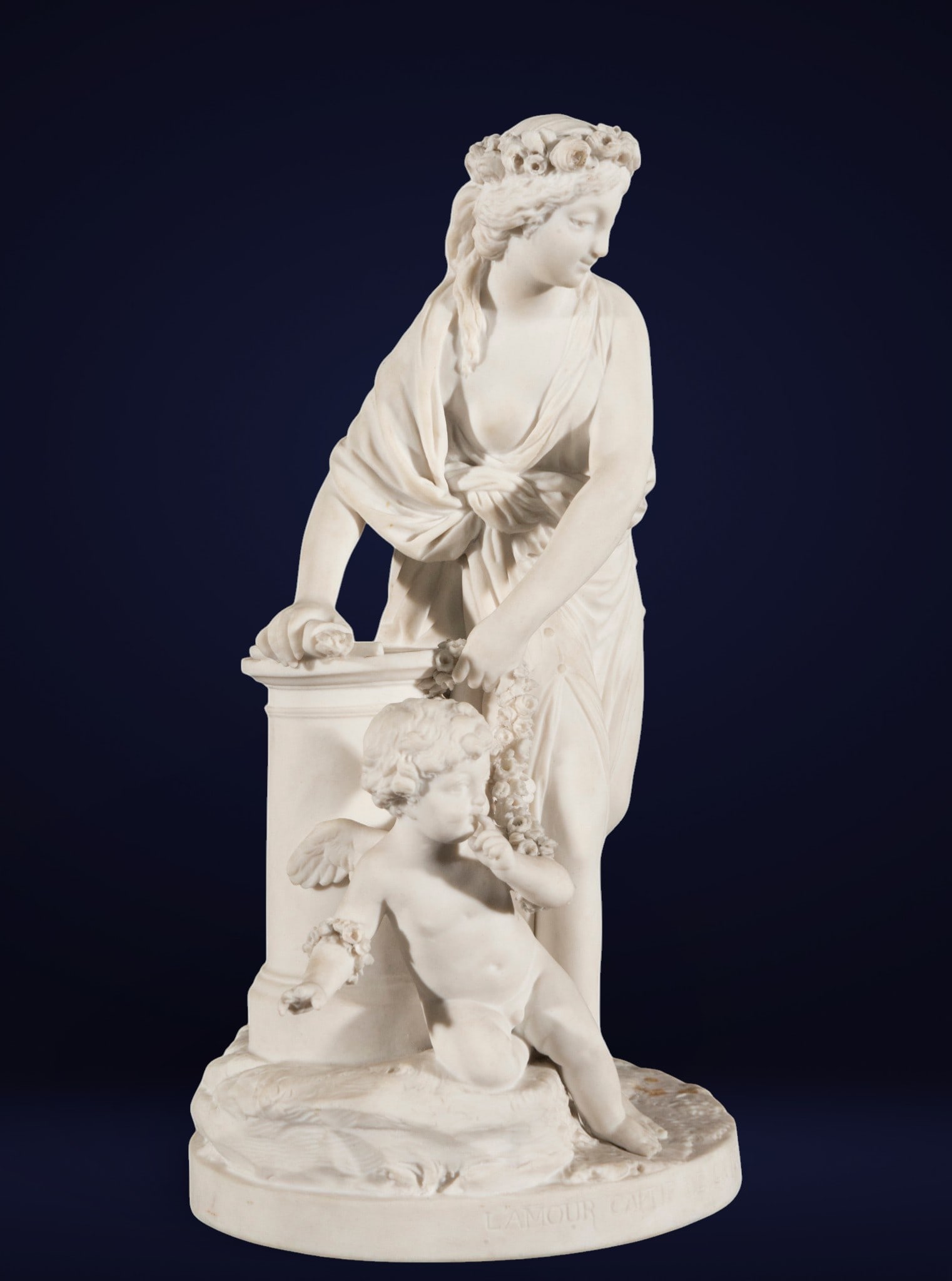 Allegorical group in French biscuit porcelain, stamped - 19th century: White porcelain. Measures 30 x 16 x 20 cm. A sculptural group of gallant inspiration featuring a female figure crowned with flowers, resting on a pedestal and accompanied by a winged cherub at her fee