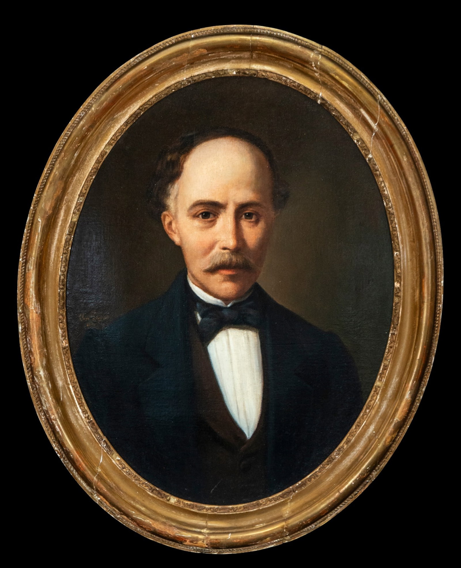 Oval portrait of a gentleman, Signed, Portuguese School, 19th Century: Oil on canvas. Dimensions 62 x 45 / 74 x 57 cm. Long bust portrait of a man in an oval format, with the subject facing forward and his serene gaze directed at the viewer. He wears a dark frock coat, w