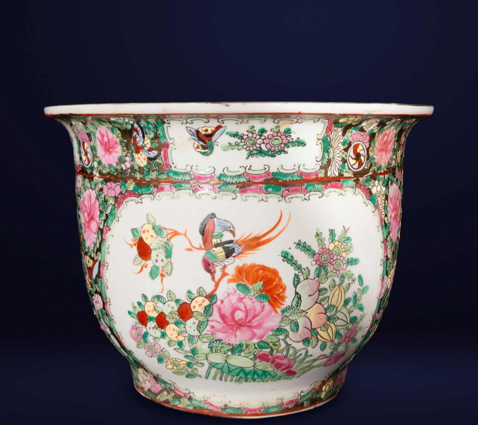 Chinese porcelain flowerpot, oriental work, 20th century: Glazed and polychrome porcelain. Dimensions: 21 x 28 x 28 cm. A wide-mouthed, slightly flared planter decorated with floral arrangements, butterflies, and birds amidst scrolls and borders of oriental 