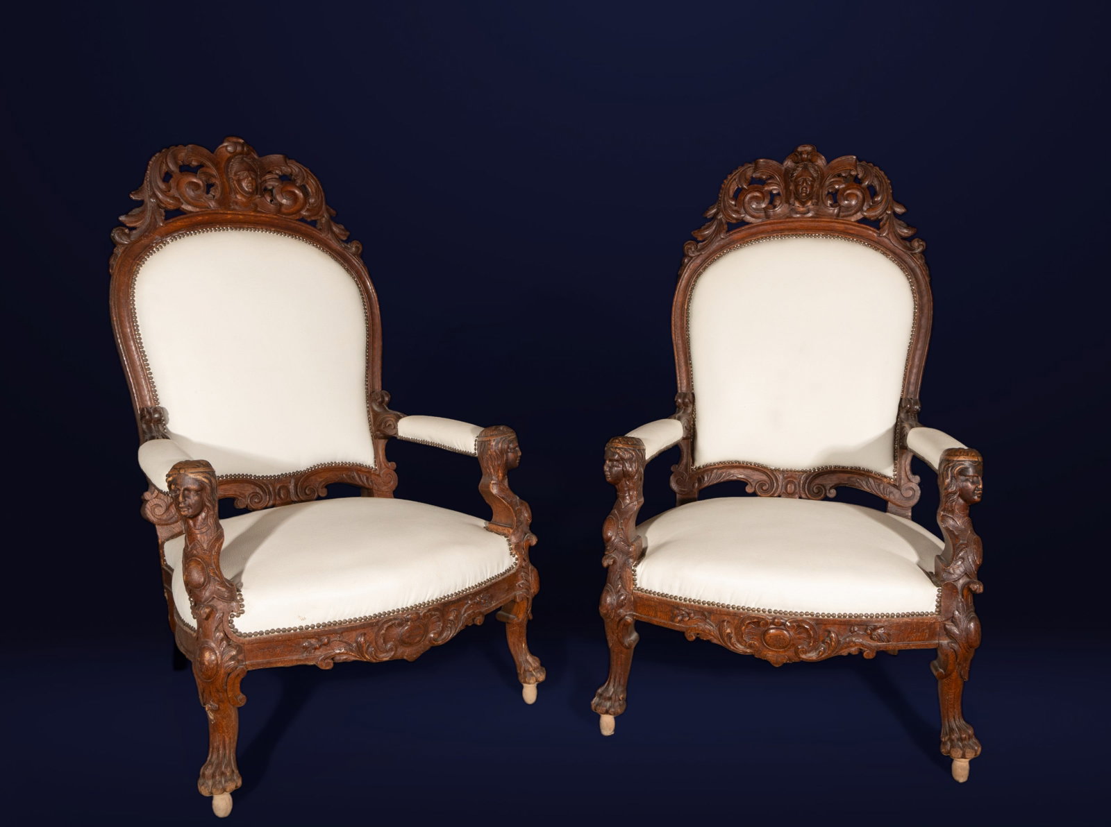 Pair of armchairs with caryatids, European school, 19th century: Carved oak and upholstery. Dimensions: 135 x 79 x 65 cm. Pair of high-backed armchairs with profuse ornamental carving, topped with scrolls and mascarons, and arms supported by sculpted female caryati