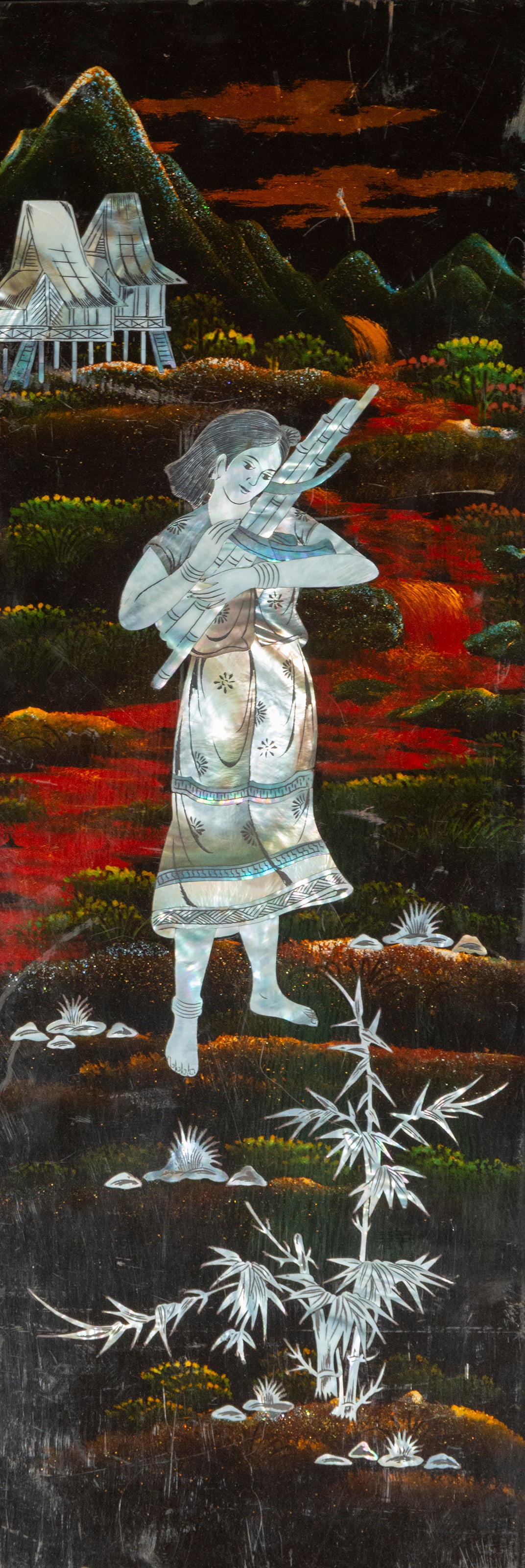 Decorative panel with mother-of-pearl inlay. Oriental art. 20th century: Rectangular panel with a black lacquered background and mother-of-pearl inlays. Dimensions: 49 x 20 cm. The scene depicts a female figure carrying a reed musical instrument, set against a mountainous 