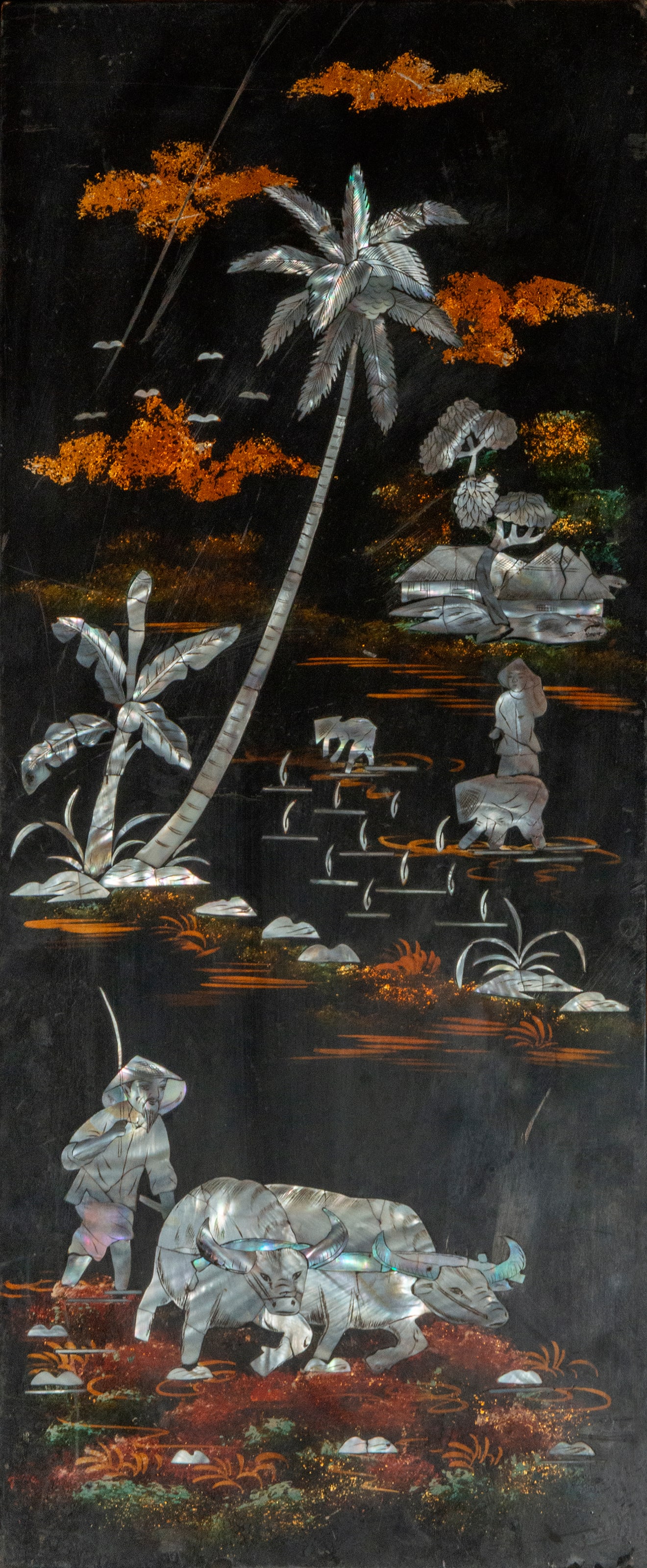 Decorative panel with rural scenes. Mother-of-pearl and lacquer. Oriental art. 20th century.: Lacquered panel with mother-of-pearl inlay. Dimensions: 49 x 20 cm. Vertical composition with a tropical landscape scene: palm trees, houses on the water, human figures, rice paddies, and buffalo. The