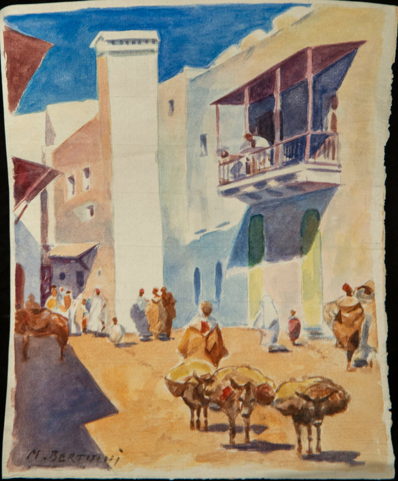 Street scene Signed M. Bertuchi Orientalist School 20th Century: Watercolor on paper. A serene Moroccan street unfolds beneath the warm light of day, flanked by whitewashed buildings in a vibrant blue evoking the chromaticity of Chefchaouen. Beneath an arch framing