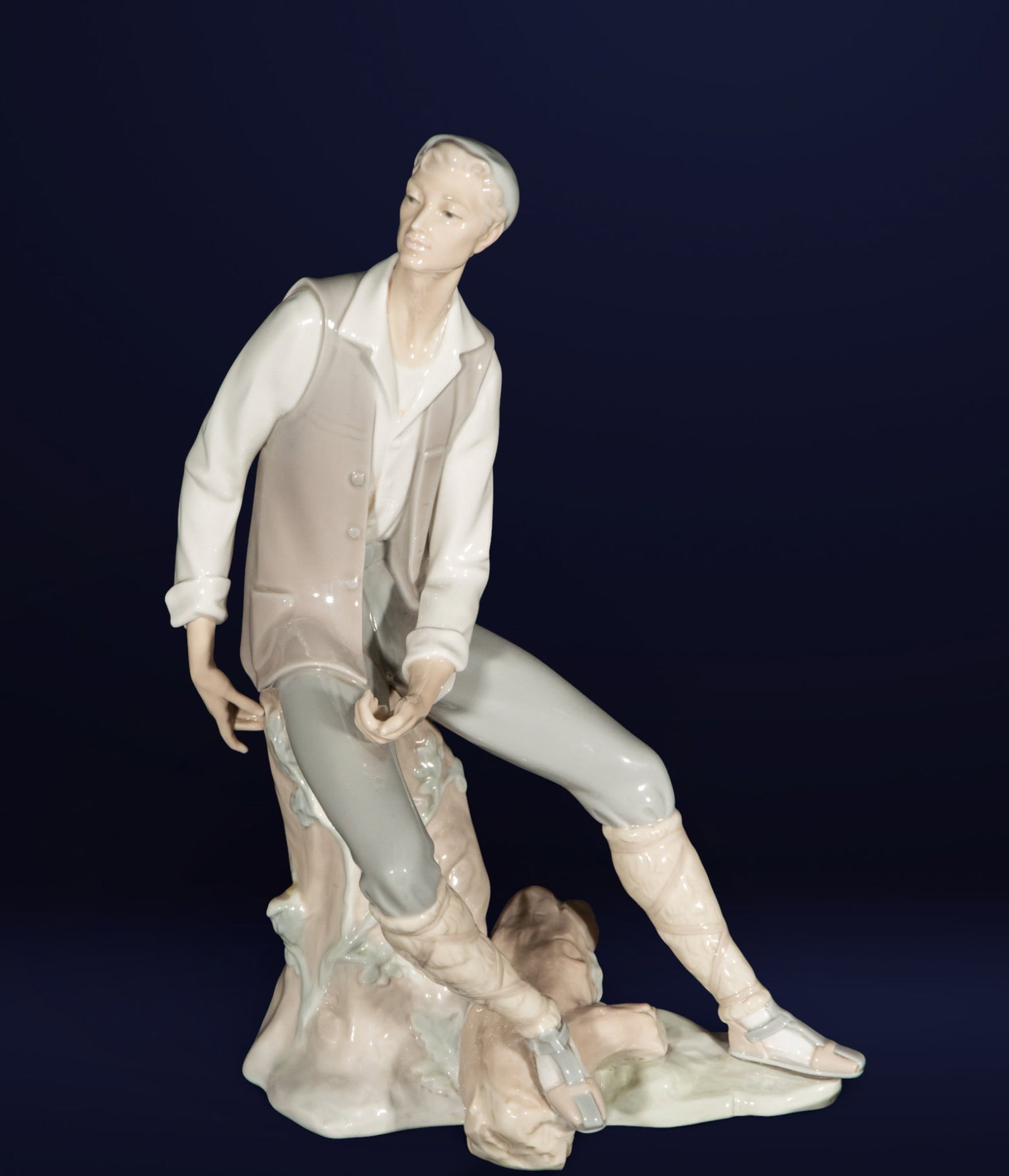 Lladró figurine 'Thoughtful Man'. Spanish School. 20th century.: Porcelain figurine from the renowned Lladró company, depicting a seated young man with a reflective expression. Dimensions: 39 x 22 x 16 cm. A piece of delicate modeling and soft tones, characteristi