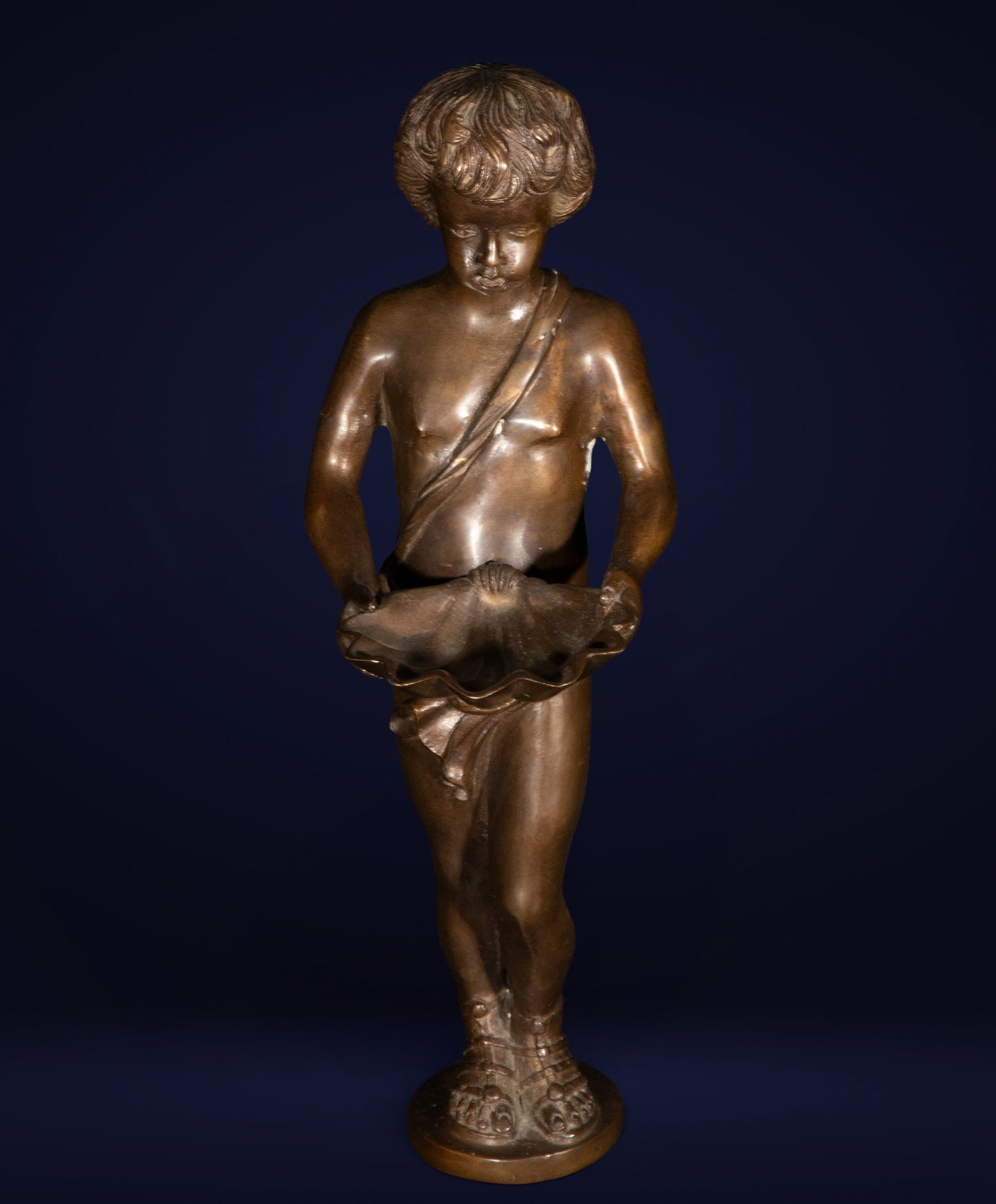Bronze figure of a boy with a shell. European school. 19th century.: Patinated bronze sculpture depicting a child holding a seashell. Finely modeled with naturalistic details. Dimensions: 43 x 16 x 17 cm. A decorative piece of classical inspiration.