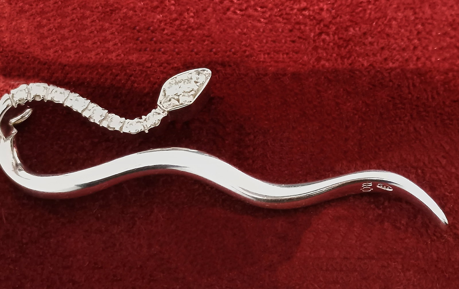 Large pendant in 18-karat white gold and diamonds, weight 4.5 g: Original pendant crafted in 18k white gold, featuring a stylized design with sinuous lines and diamond accents. It bears jewelry hallmarks and the 750 hallmark. Weight: 4.5 g.