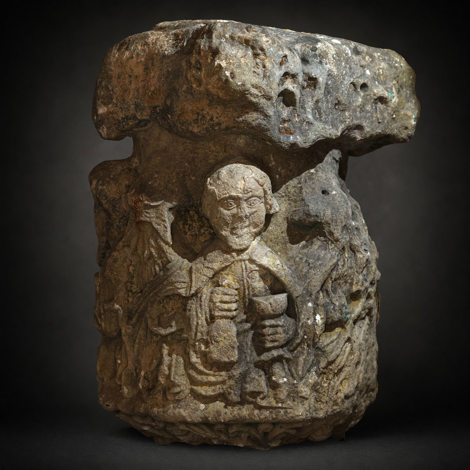 Exceptional Romanesque Cross Base from the 13th Century: 60 x 44 x 46 cm. Carved from stone, possibly from Salamanca or Galicia. A figure, the best preserved of the group, stands out around the base of the wayside cross, holding a chalice and a Bible. Could