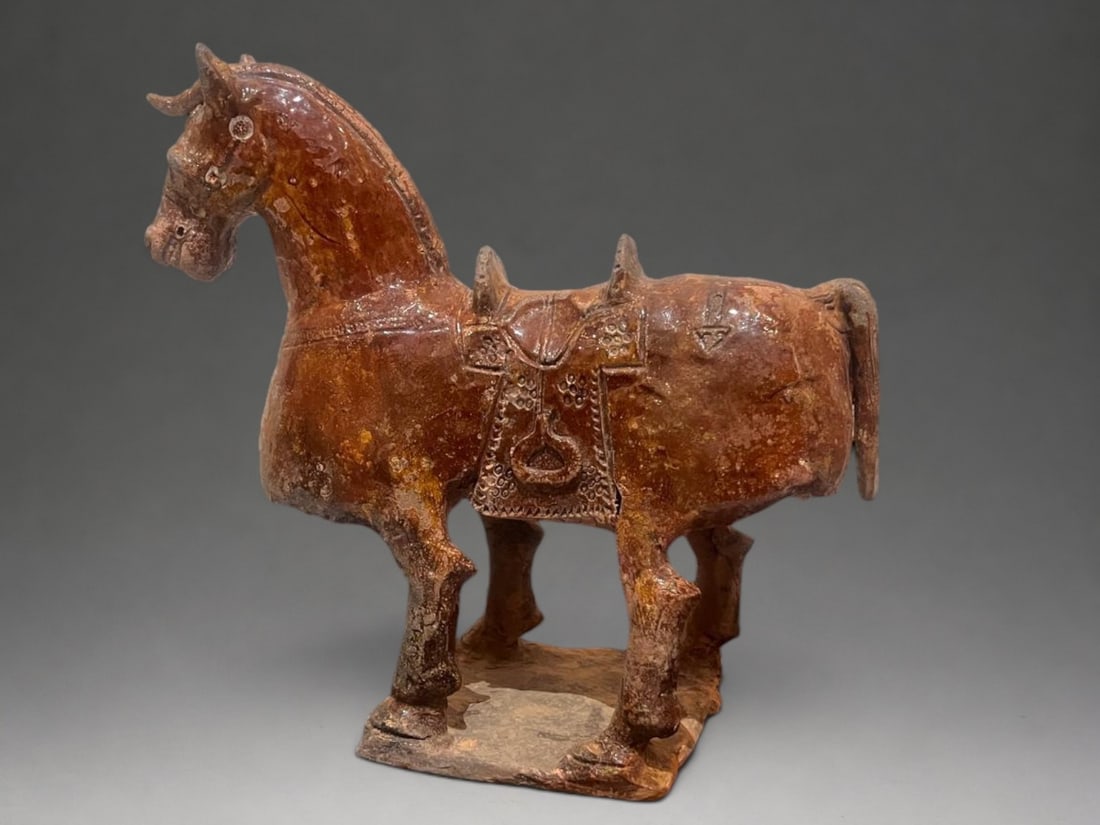 Funerary horse Mingqi, Chinese school, 3rd - 6th century: Partially glazed terracotta in an amber-brown tone. Measures 29 x 33 x 13 cm. Figure of a funerary horse standing on a rectangular base, with its head slightly inclined forward and its ears erect. The