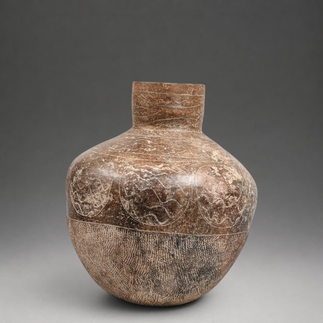 Ban Chiang Vase, Thailand, 15th-5th century BC.: Modeled and incised terracotta. Measures 38 x 12 cm. Important globular jar with a slightly open cylindrical neck and decoration arranged in horizontal registers of sinuous and undulating motifs inscr