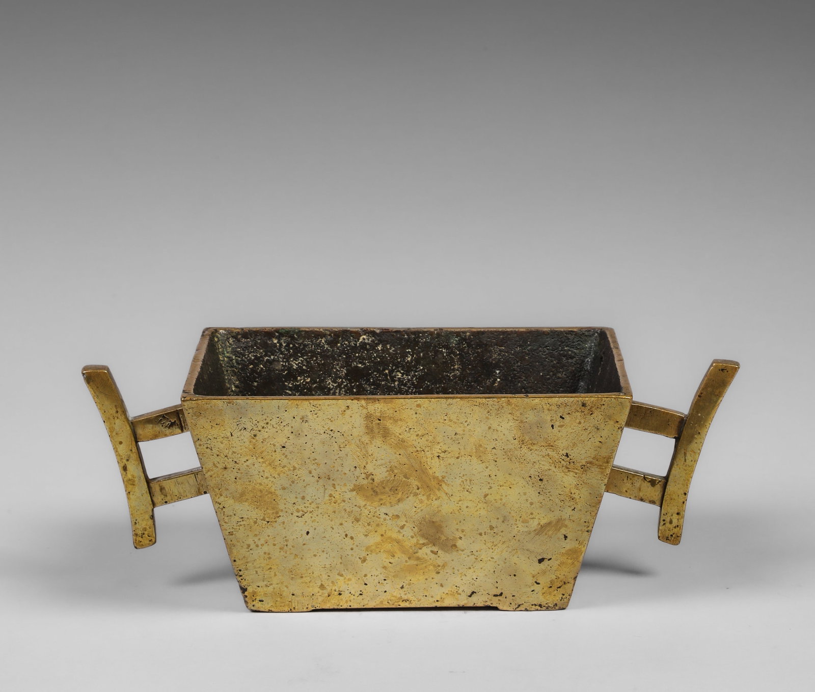 Square incense burner with side handles, Qing Dynasty Chinese school, 19th century: Cast and patinated gilt bronze. Measures 9 x 24.5 x 16 x 12 cm. Incense burner with a slightly trapezoidal, quadrangular structure and two geometric side handles that visually extend the piece's horiz