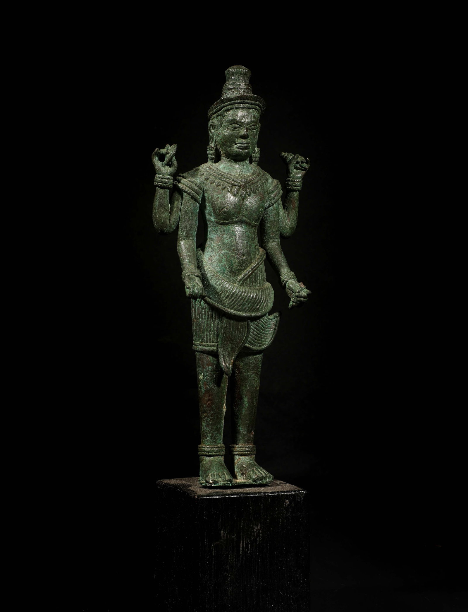 Four-armed Vishnu, Khmer school, 12th-13th century: Bronze with a green patina from excavation. Approximately 45 cm high. Sculpture of Vishnu depicted standing in a hieratic pose with four arms, holding in his upper hands the chakra and the ritual shan