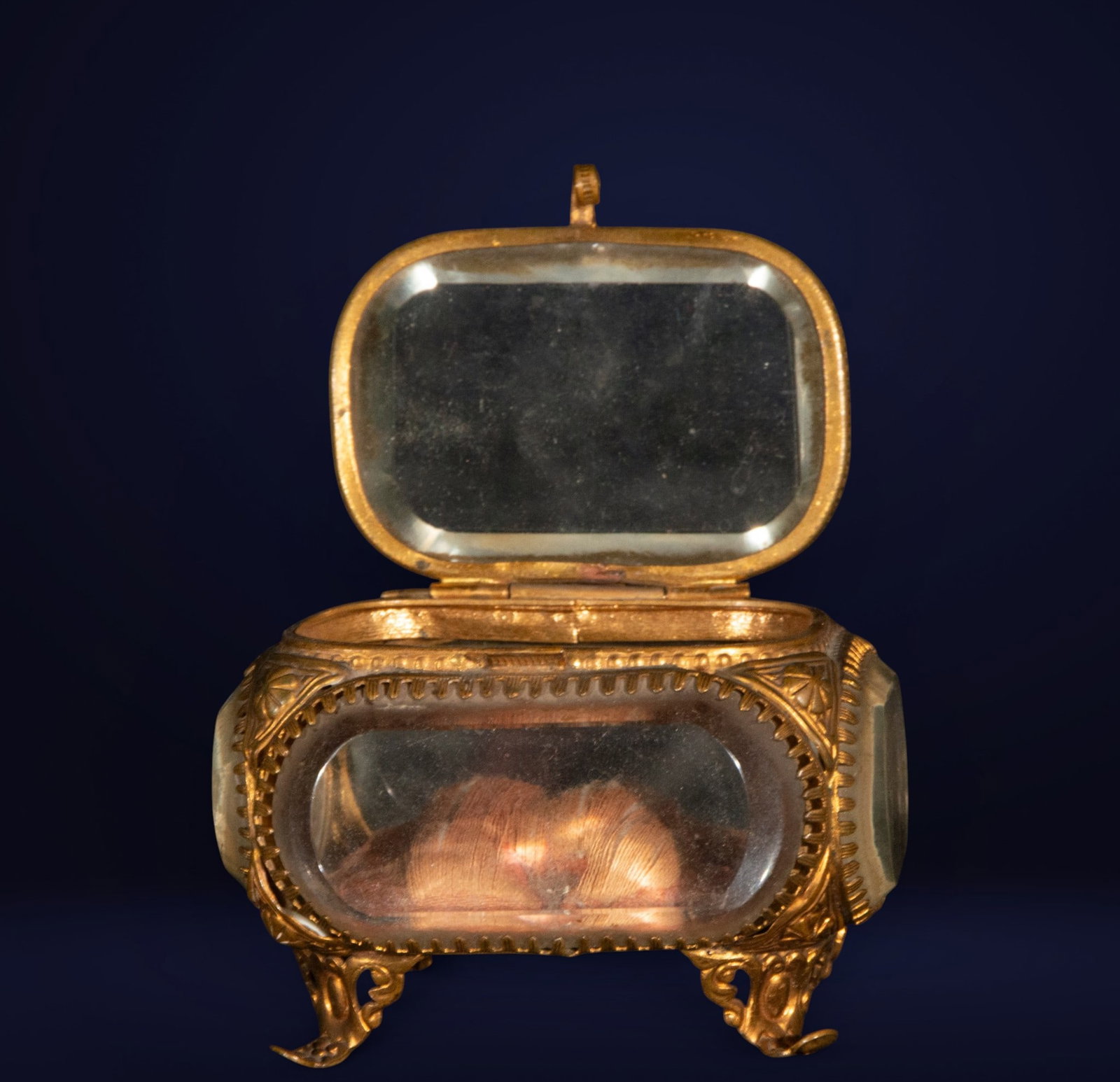 Elizabethan jewelry box, Spanish School, 19th century: Gilded metal and beveled glass. Dimensions: 6 cm x 9 cm x 8 cm. Small jewelry box in the Elizabethan style with an ornate metal frame featuring scrollwork and Rococo-inspired legs. The beveled glass a