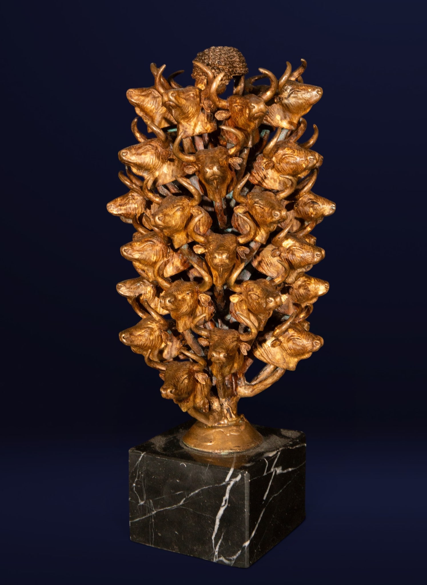 Bronze sculpture with bull heads, Contemporary School, 20th Century: Patinated bronze on a marble base. Dimensions: 30 x 12 x 14 cm. This sculpture features a complex vertical composition formed by numerous bull heads intertwined by curved horns and surmounted by a fig