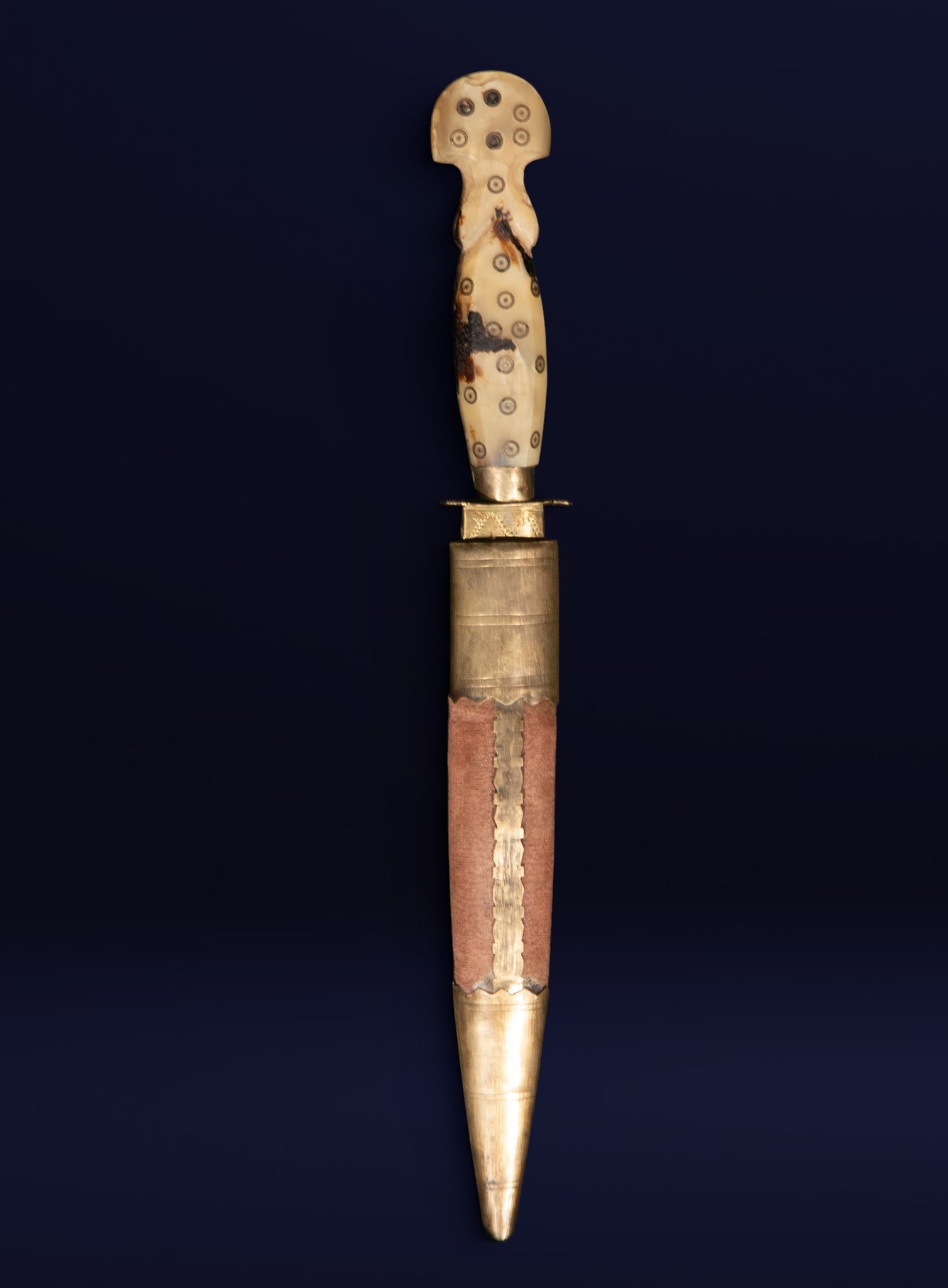Dagger in horn and bronze, Oriental School, 18th Century: Steel, horn, and engraved bronze. Dimensions: 30 x 3 x 2 cm. Small dagger with a horn handle decorated with circular metal inlays and a leather-covered scabbard with bronze appliqués. The straight bl