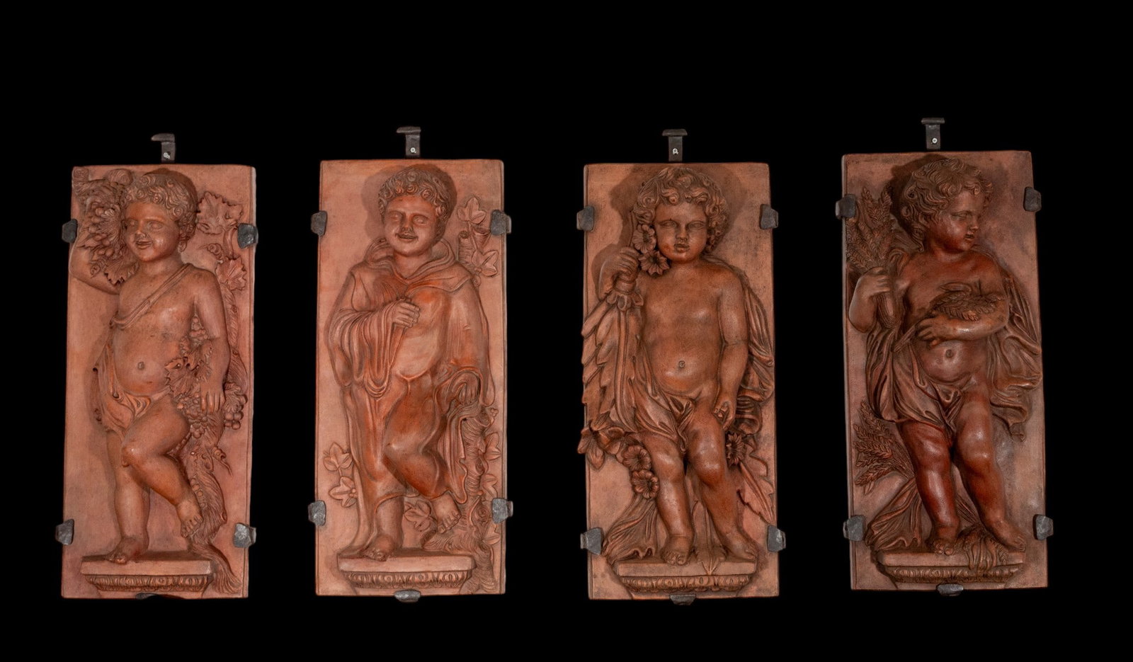 Reliefs with little angels of the four seasons, European School, 19th Century: Modeled terracotta. Dimensions: 70 x 30 x 14 cm. Set of four terracotta reliefs with cherubs alluding to the four seasons, arranged on rectangular plaques and accompanied by plant and agricultural ele