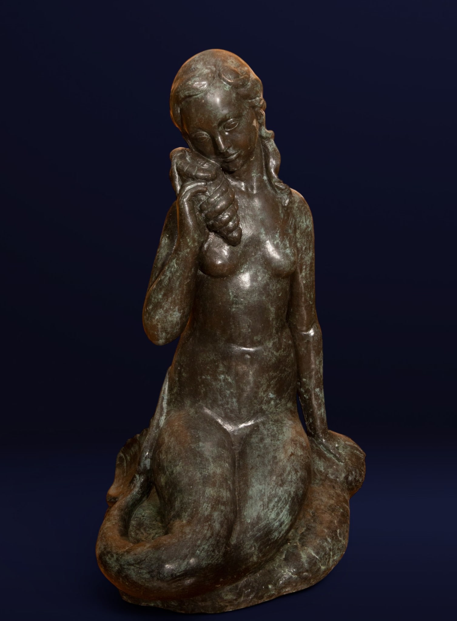 “Mermaid??, Agustí Guasch Gómez, Signed, Catalan school, 20th century: Patinated bronze sculpture. Allegorical nude female figure depicted in a serene pose holding a seashell, with soft modeling and a Mediterranean-inspired composition. The piece features a natural green