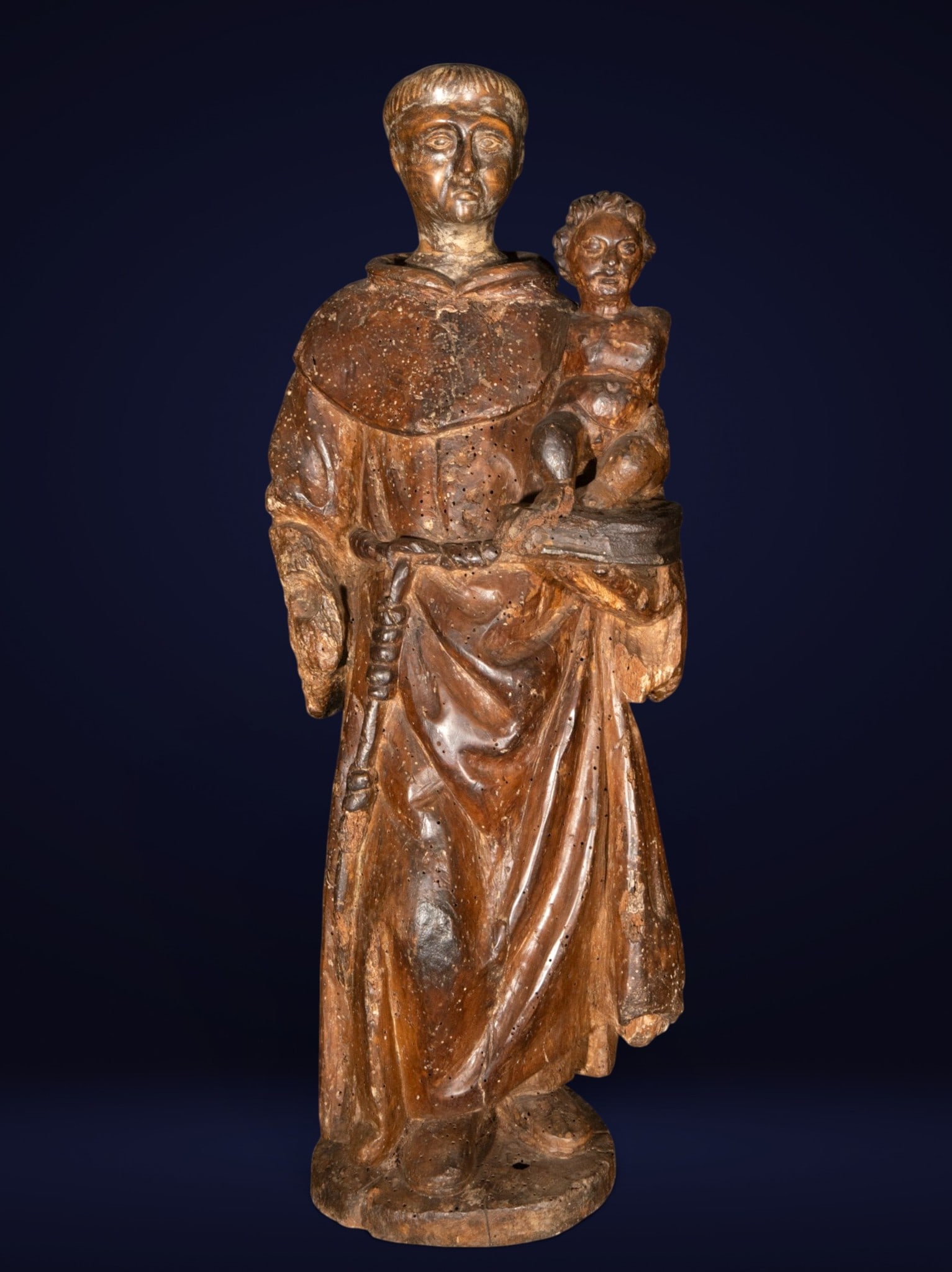 Saint Anthony with the Child, Goan school, India, 16th century: Wooden sculpture. Image of Saint Anthony of Padua holding the Christ Child on a book, accompanied by a rosary and a Franciscan habit with flowing folds. The composition is notable for the serenity of 