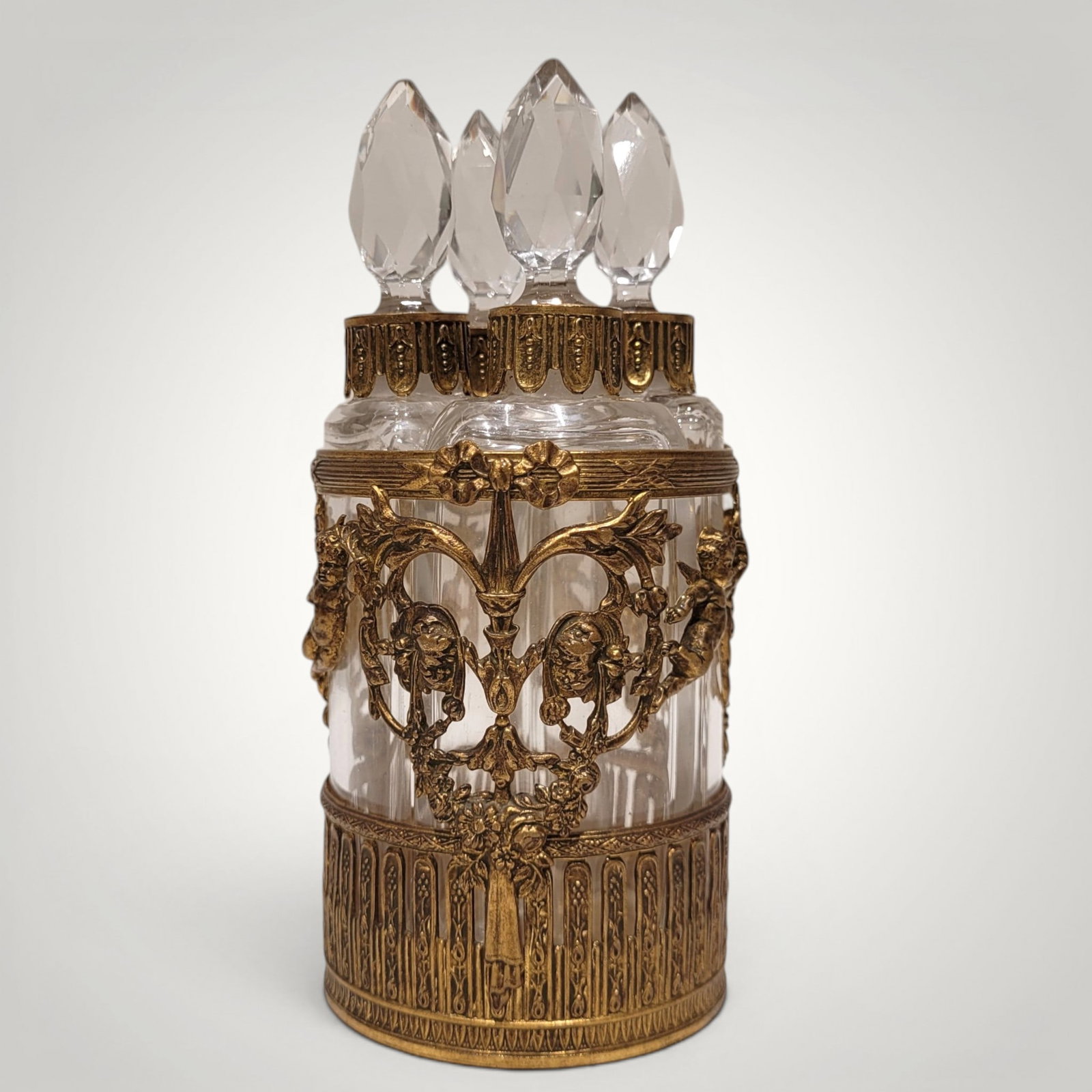 Napoleon III Perfume Dispenser, French School, 19th Century: Molded crystal and gilt bronze. Measures 14 x 6 x 6 cm. A refined vanity set composed of four small faceted crystal containers topped with carved prismatic stoppers, arranged in a profusely ornamented