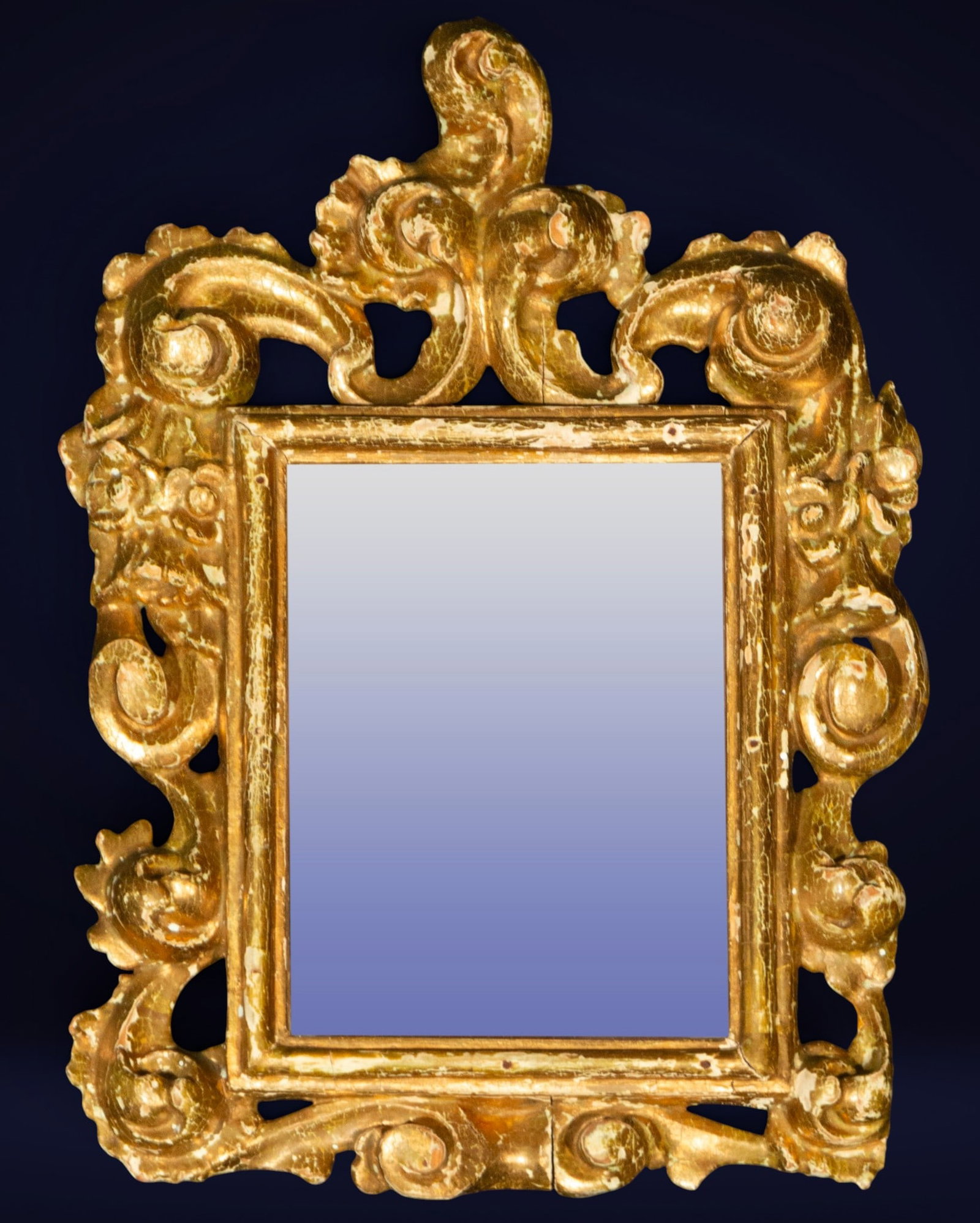 Spanish Baroque mirror, Spanish School, 18th-19th century: Carved and gilded wood. Measures 45 x 31 cm. Rectangular mirror framed by an exuberant Baroque carving with pronounced vegetal scrolls and a stylized acanthus leaf finial. The ornamental composition u