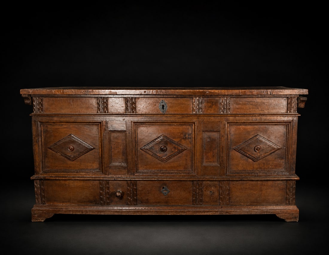 Walnut chest with lower drawer, Spanish School, 18th Century: Carved and molded walnut wood with iron fittings. Measures 63 x 131 x 53 cm. This chest, with its architectural lines, consists of a hinged upper section and an integrated lower drawer, decorated with