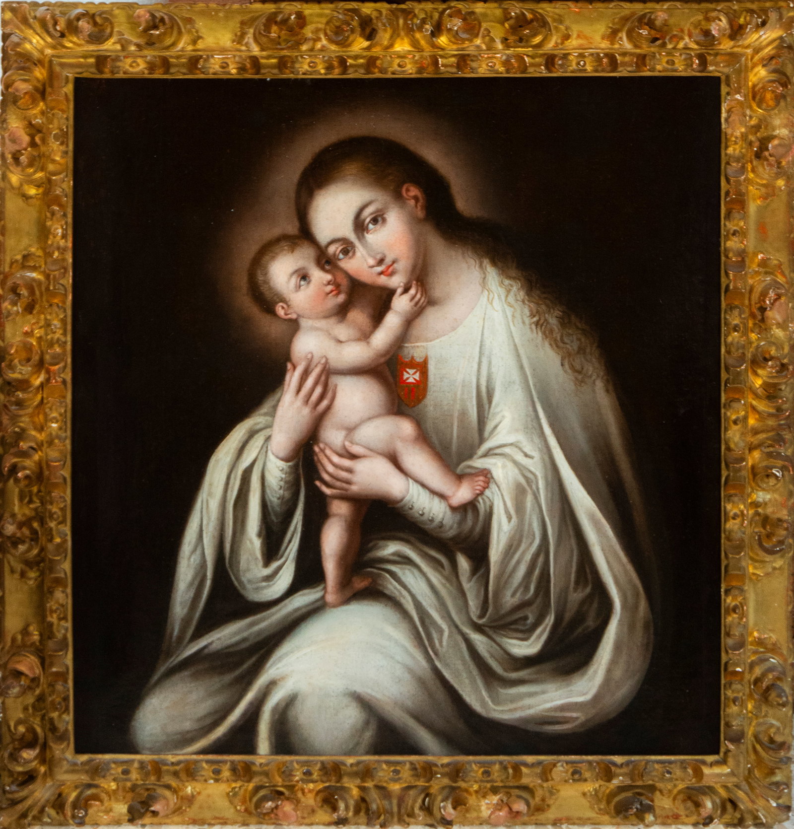 Virgin and Child. New Spanish School. 18th century: Oil on canvas. The painting captures a devotional depiction of the Virgin Mary holding the Child Jesus in a tender and protective attitude. Both faces appear delicately close, with expressions of idea