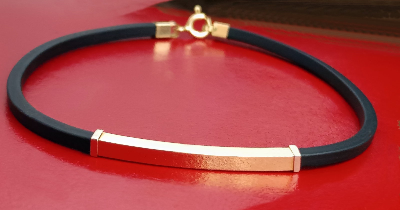 Unisex 18k gold bracelet with Italian design, Italian, 20th Century: Unisex bracelet made of solid 18-karat gold, with black rubber and a square, elongated top plate measuring 3.3 cm, with a uniform thickness of 3 mm on all four sides. The interior features a small emb