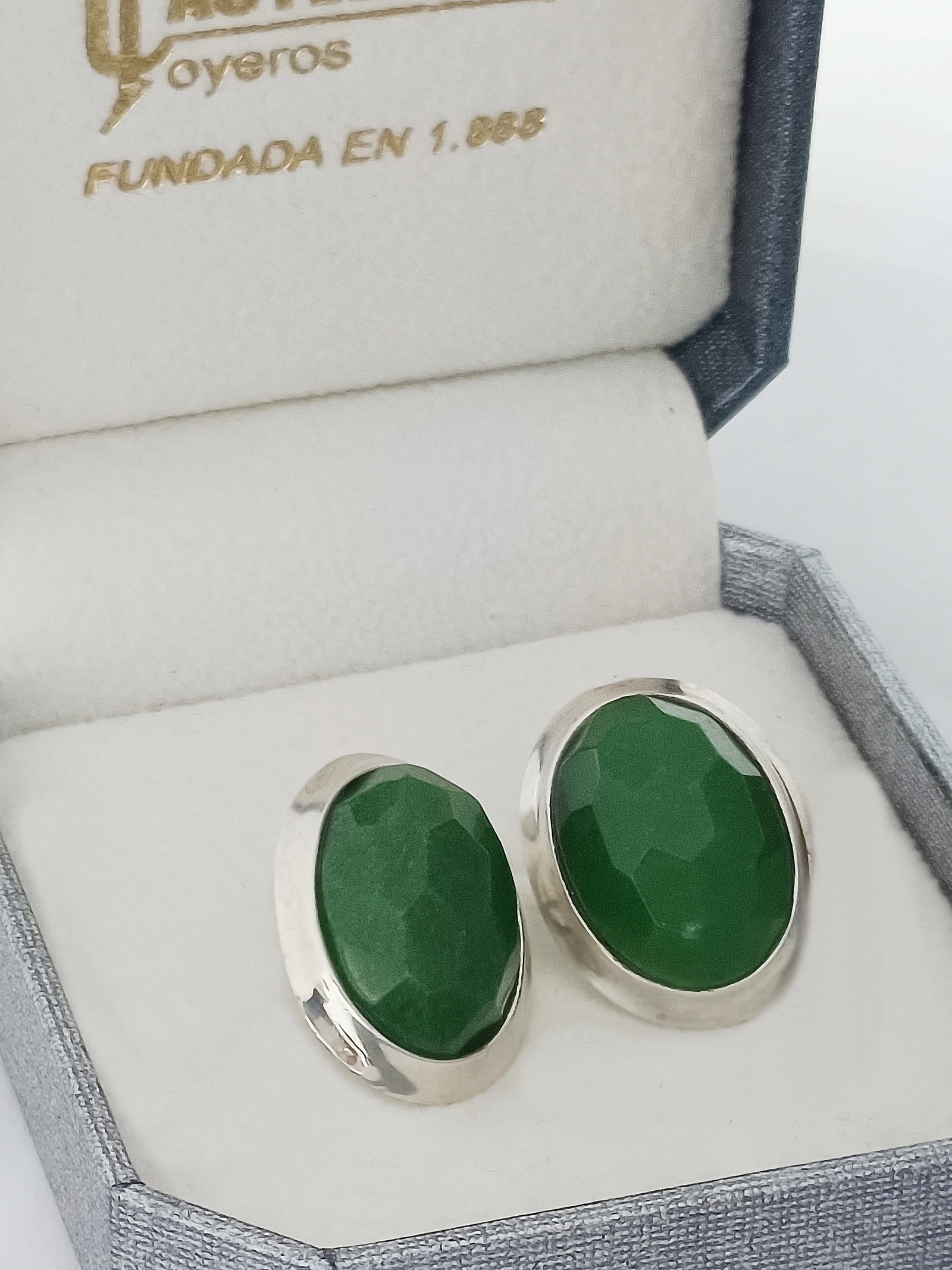 Natural jade and sterling silver earrings, Vintage, 20th Century: Large vintage earrings with untreated natural emerald green jade, in an oval cabochon cut with fine faceting, surrounded by a canopy and sterling silver settings with hallmarks 925. Measurements: 2.2 