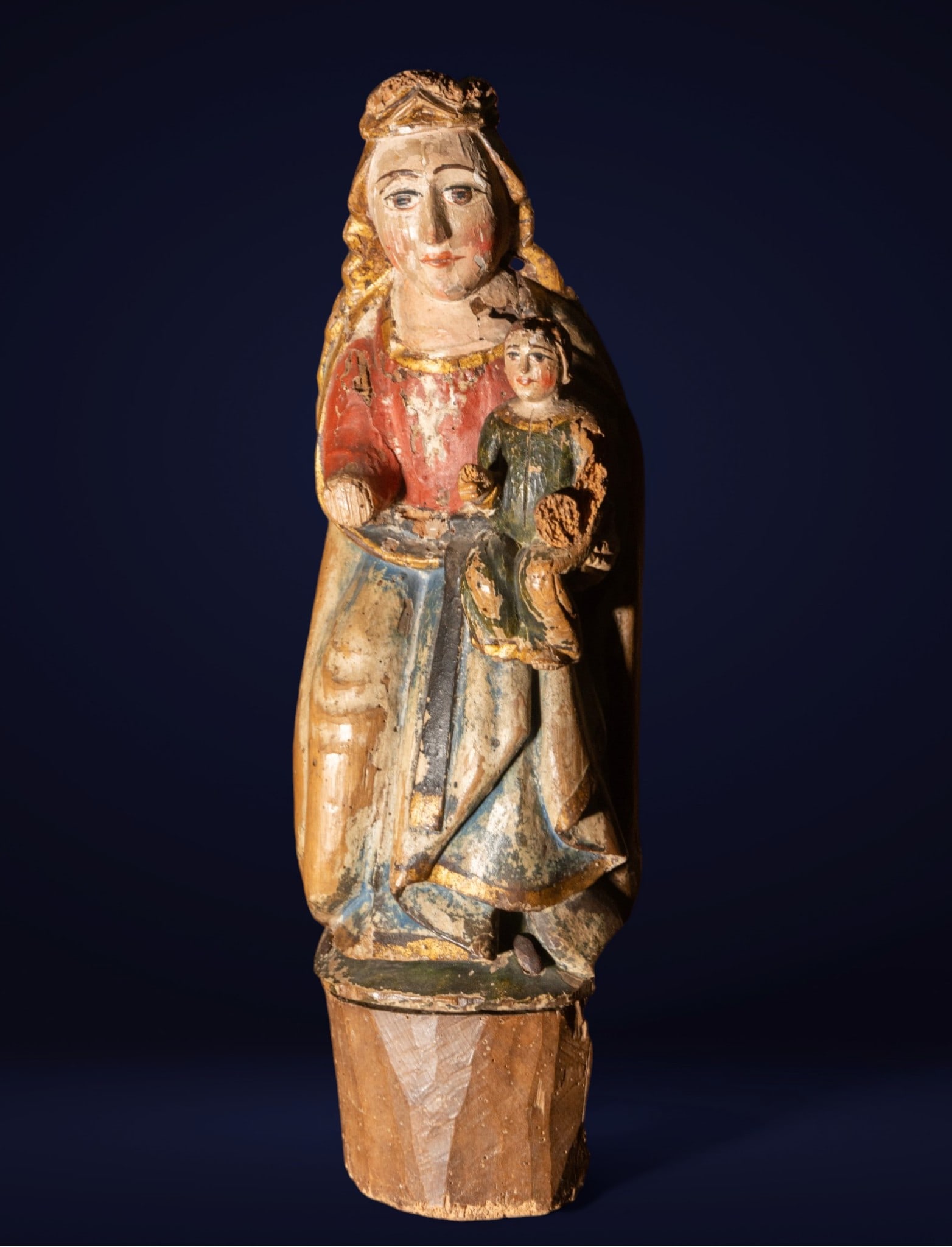 Virgin and Child Seated, Gothic School, 14th Century: Virgin and Child. Measures 59 x 21 x 15 cm. Small seated image of the Virgin with a crown and veil, holding the Child on her left knee. The Mother raises a hand holding a piece of fruit, while the Chi