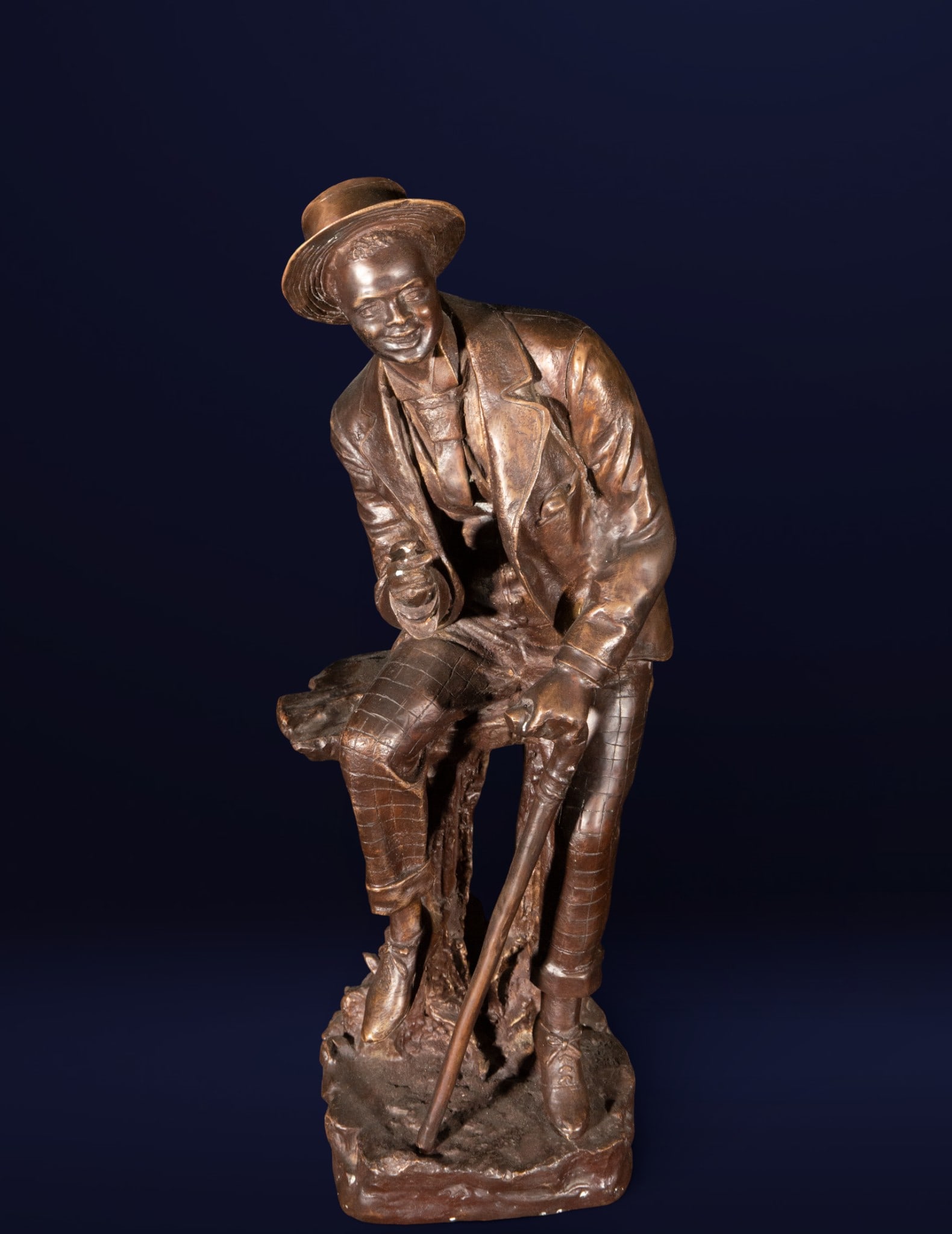 The Smoker. Bronze sculpture. European school. 20th century.: Cast bronze. Measures 55 x 21 x 20 cm. Figurative sculpture of a seated male figure, leaning slightly forward, captured in the everyday gesture of smoking while resting a cane between his legs. The re
