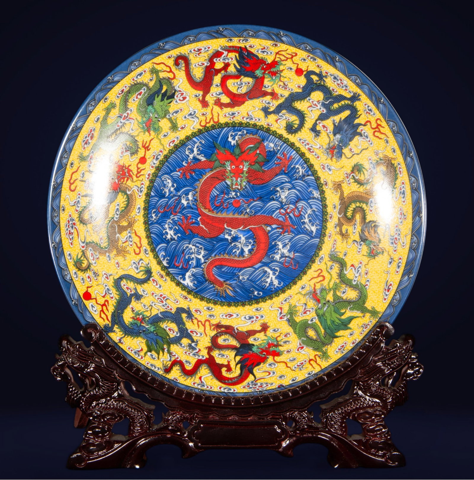 Decorative and large Chinese plate with stand, 20th century: Porcelain. Measures 36 x 36 x 2 cm. Polychrome plate with a large red dragon in the central medallion on a blue background, surrounded by other dragons of different colors among clouds on a yellow bac