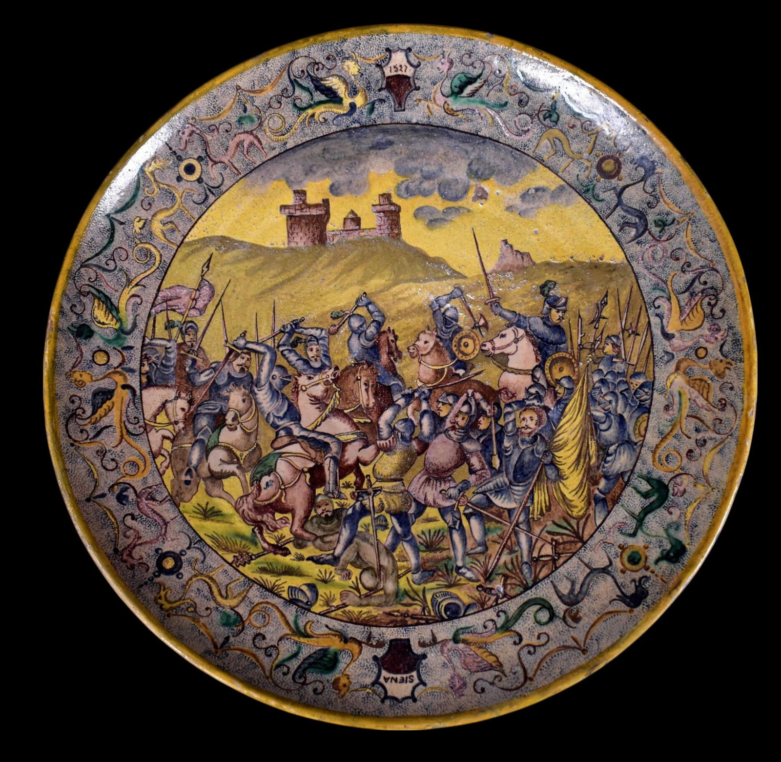Large round Tuscan plate (Siena) from the 18th century: Large round Tuscan (Siena) plate from the 18th century, decorated with a battle scene. Marked Siena with the date 1527 on the wing. Italian majolica. Diameter: 45 cm. Good condition for the period.