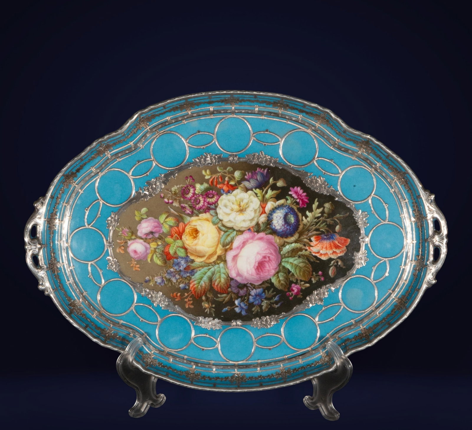 Magnificent Sèvres porcelain tray, 1857, 19th century, mounted in silver.: Sèvres porcelain with silver appliqués. Measures 41 x 32 x 3 cm. Oval tray with side handles, turquoise rim, and metal mesh ornamentation, centered by a richly colored floral medallion against a dar