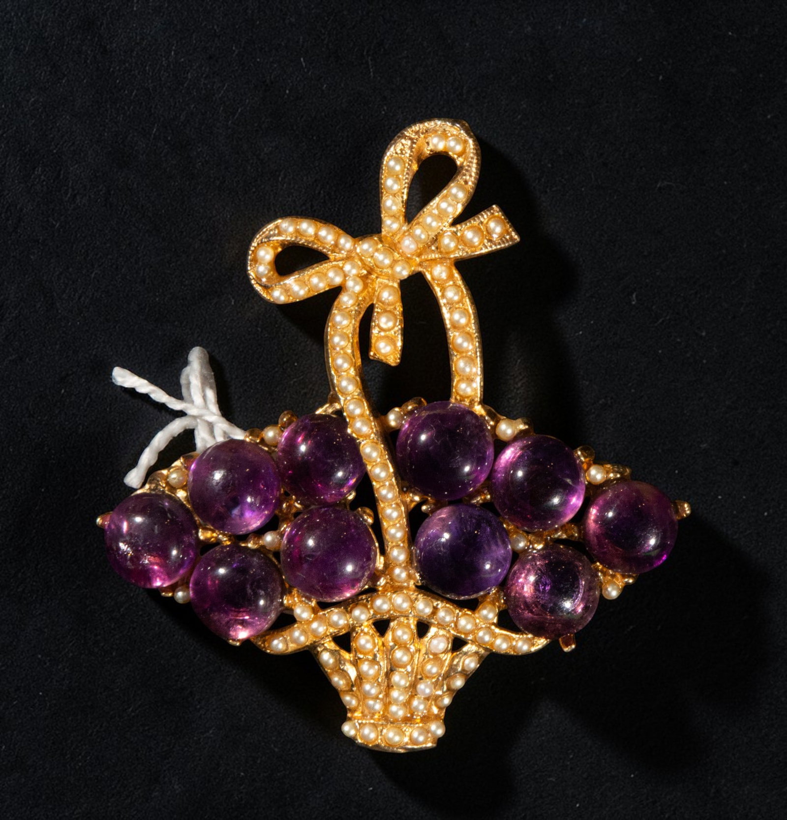 Gold-plated silver brooch with amethysts: Gilded silver brooch with amethysts. Designed in the shape of a basket topped with a bow, it features a cluster of rounded amethyst cabochons in a violet hue, arranged as the central motif on a gilded