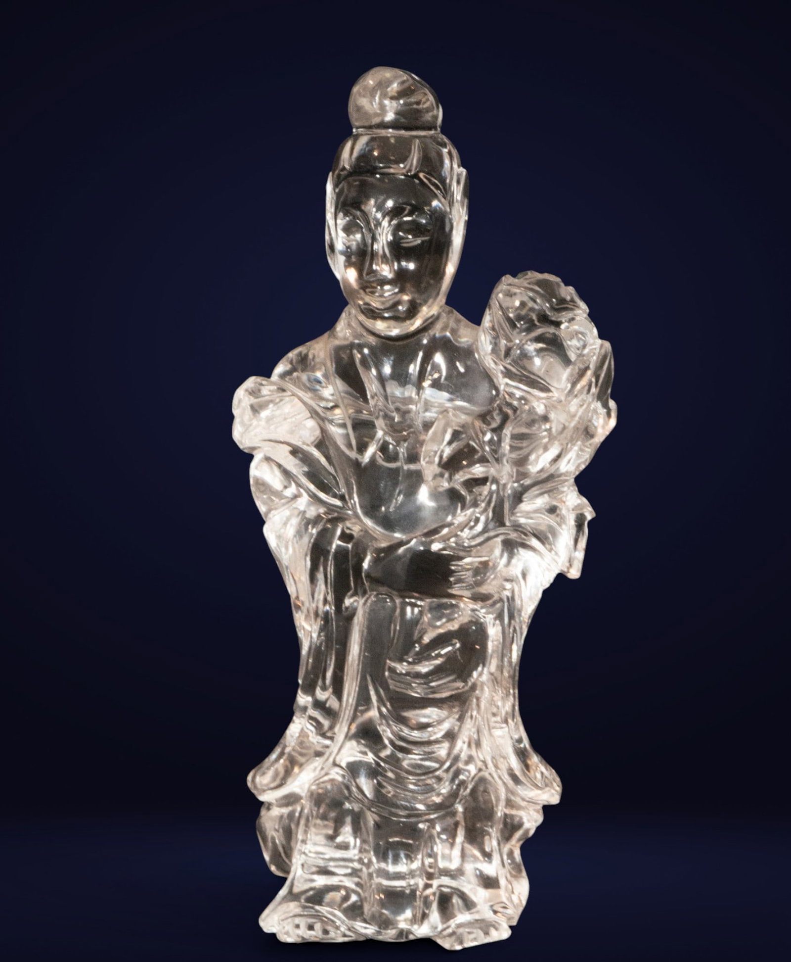 Guanyin figurine in rock crystal. Chinese School. 20th century: Carved rock crystal. Measures 15 x 7 x 5 cm. Sculpture depicting Guanyin, the bodhisattva of compassion, seated serenely amidst flowing folds. The transparency of the material and the fineness of the 