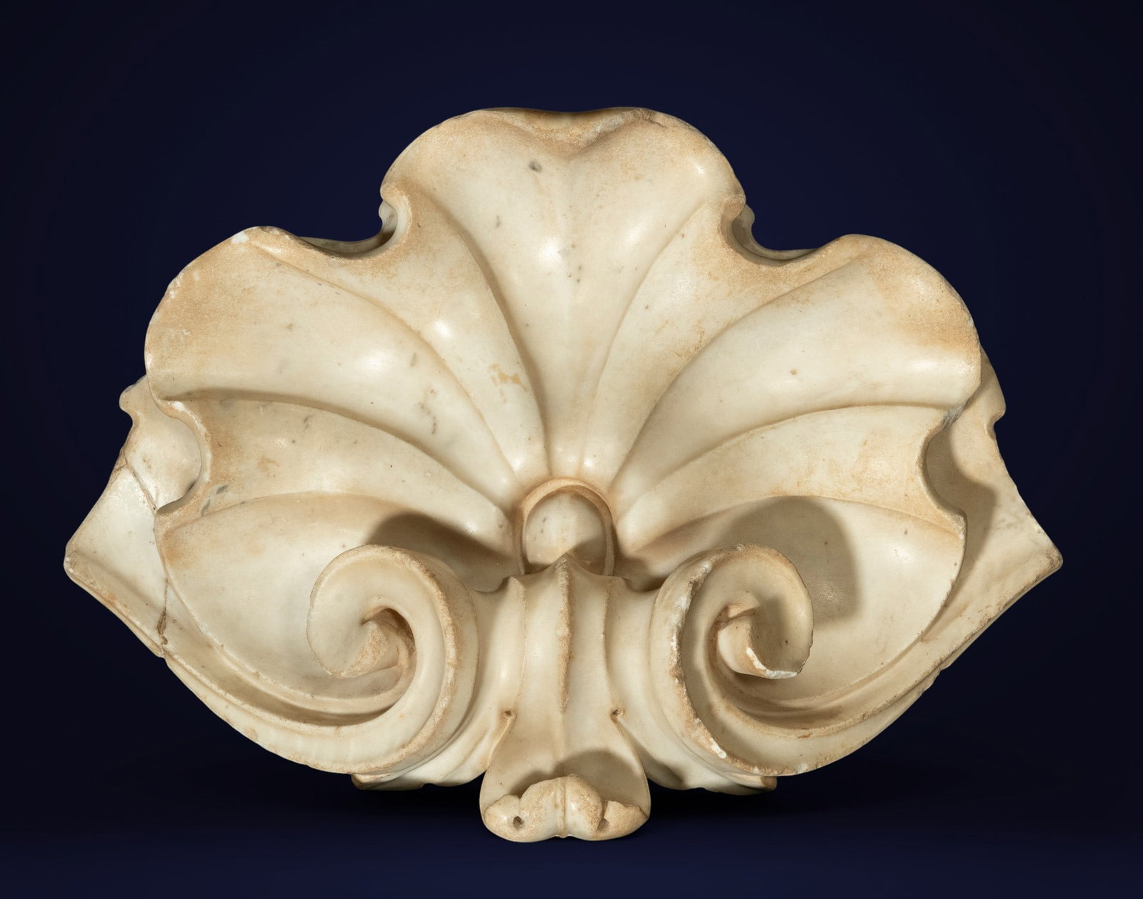 Finial of a niche or aedicule, Italy, 17th century: Carved white marble. Dimensions: 50 x 33 x 15 cm. This piece is an elegant architectural finial made of white marble, originally designed to crown a niche, shrine, or ornamental structure of a religio