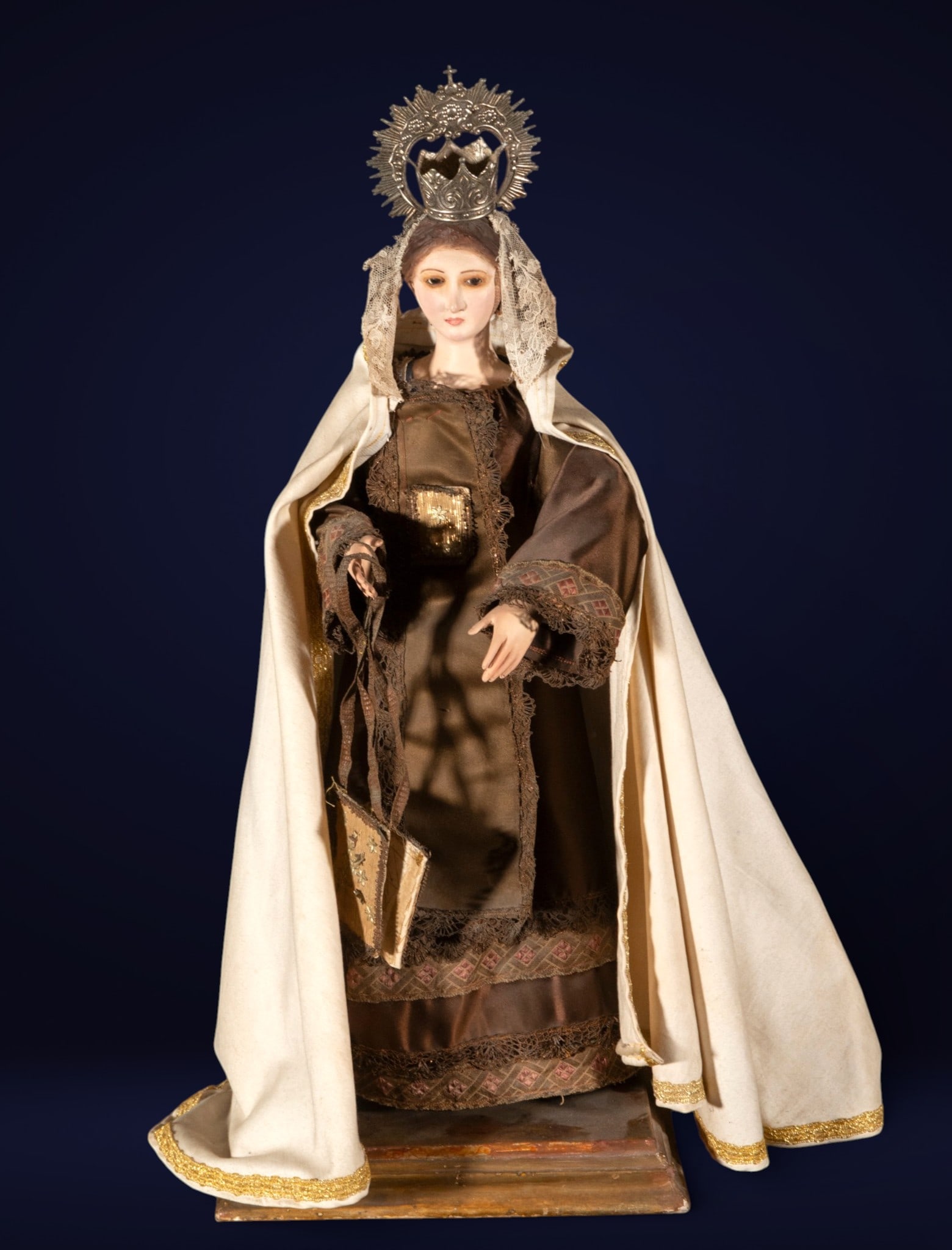 Our Lady of Mount Carmel, Philippine school, silver crown: Dressed sculpture with polychrome head and hands, probably mounted on a frame. Measures 60 x 28 x 18 cm. Silver crown.