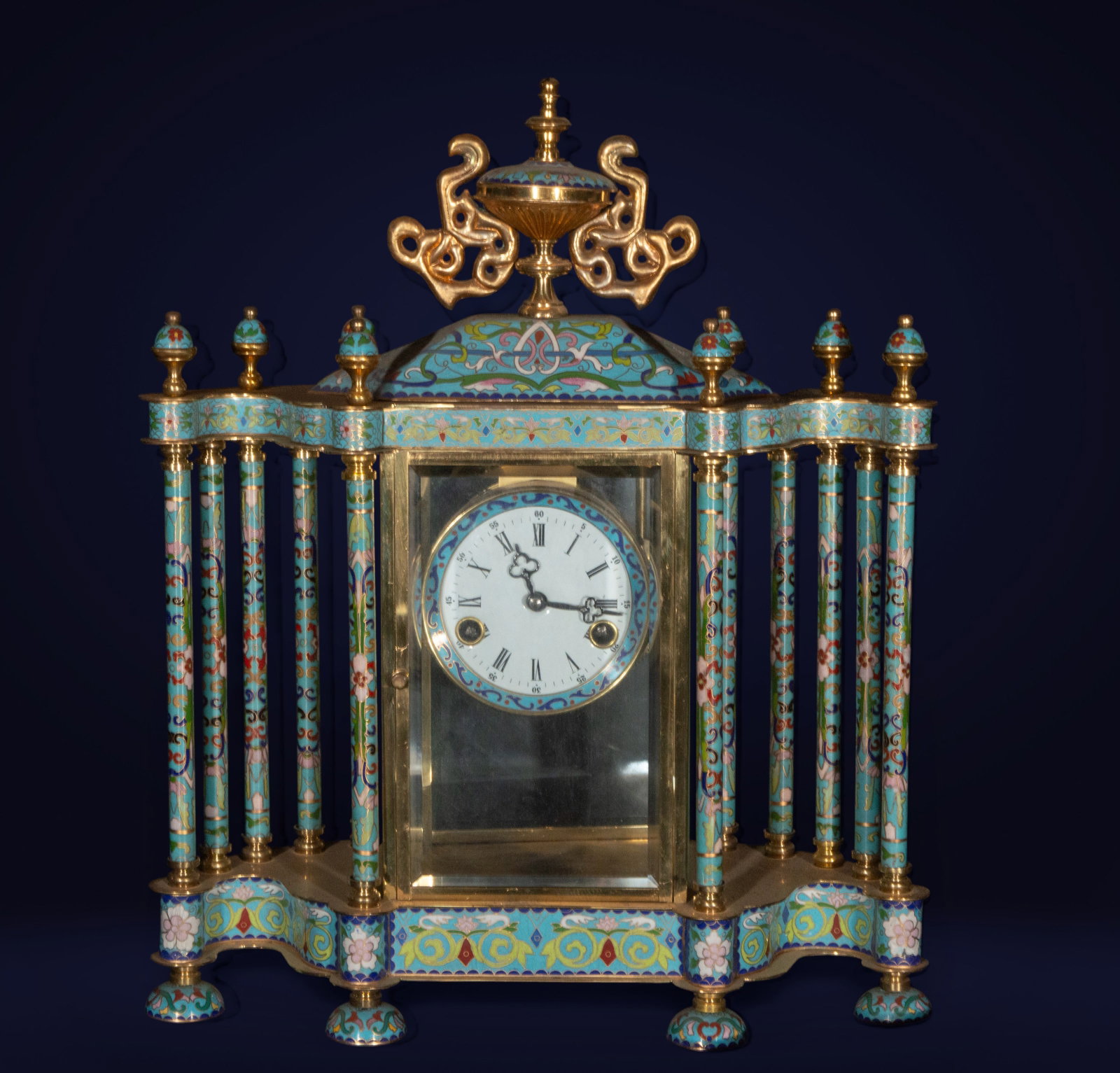 Cloisonné mantel clock, oriental work, 19th-20th century: Gilded metal and cloisonné enamel. Dimensions: 50 x 11 x 18 cm. This mantel clock features an architectural structure with side columns and an urn-shaped top, lavishly decorated with cloisonné ename