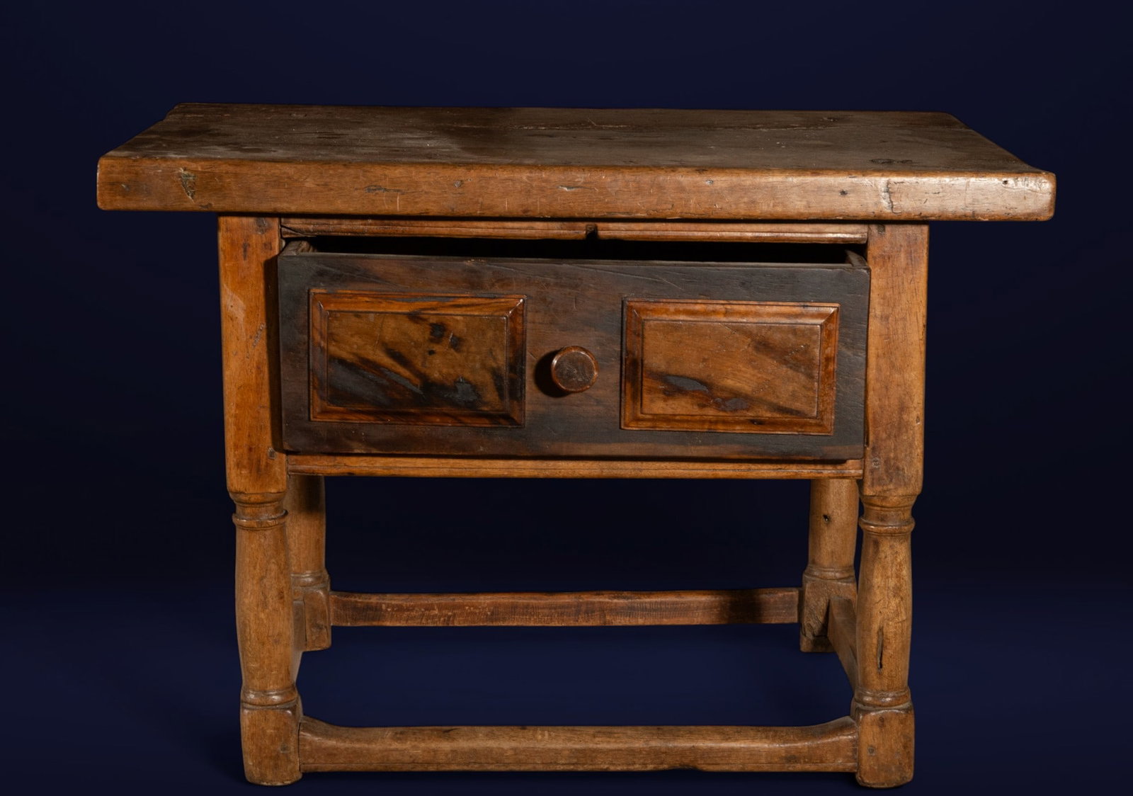 Table with central drawer. Spanish School. 18th century: Walnut wood with burr walnut appliqués. A solid Spanish table for domestic use, crafted in walnut with a single large front drawer and central handle, decorated with molded burr plates, providing an 