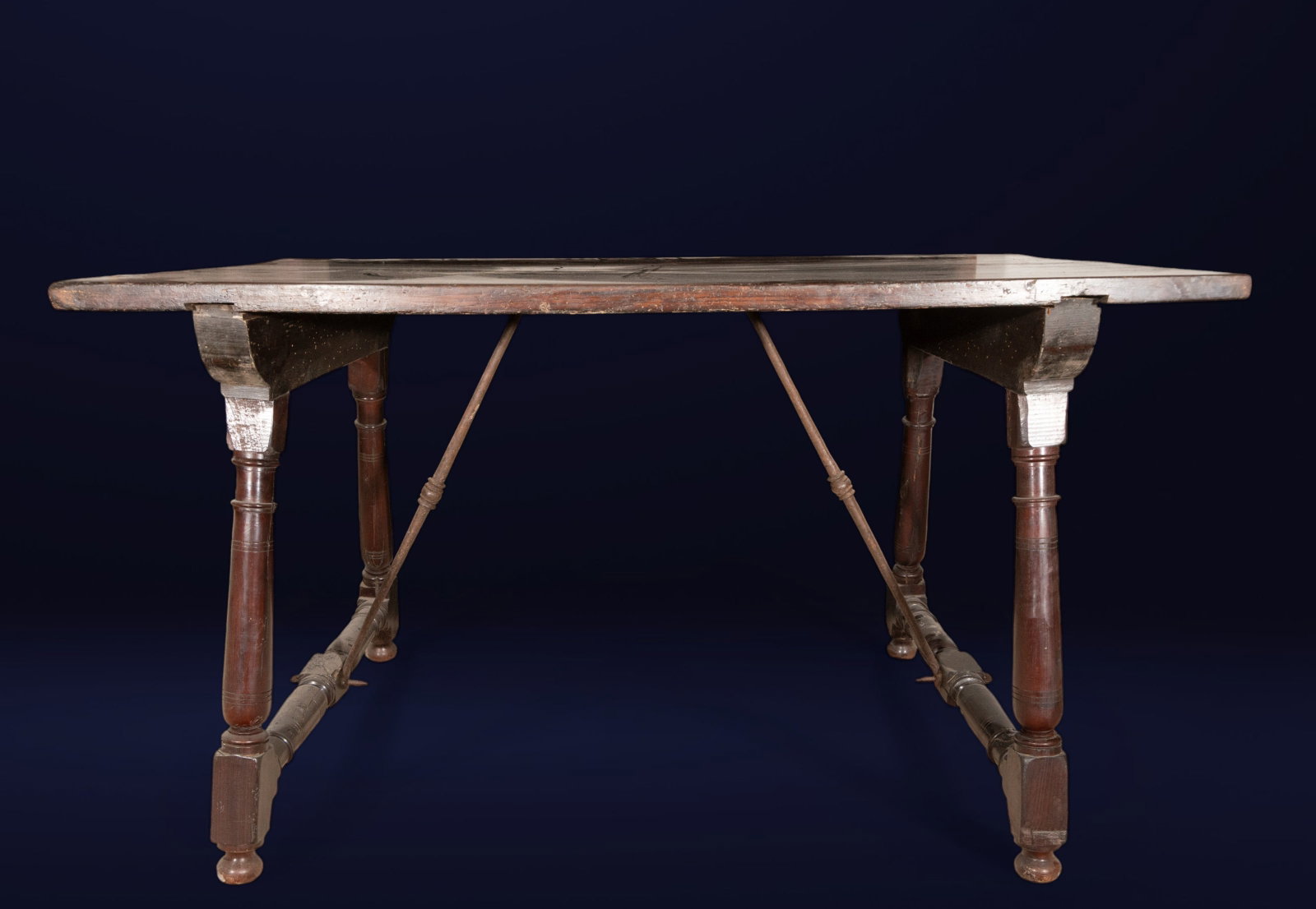 Walnut table with candle legs, Spanish school, 17th century: Walnut. Dimensions: 80 x 136 x 80 cm. A table with clean lines, featuring a large rectangular top and turned, sail-like legs joined by iron crossbars and braces that reinforce its stability. The auste