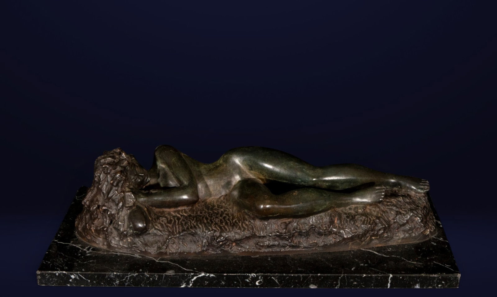 Reclining woman. Contemporary school. 20th century: Patinated bronze. Measures 11 x 51 x 24 cm. Sculpture of a reclining nude female figure on a naturalistic base. The composition stands out for the serenity of the pose, the fluid treatment of the form