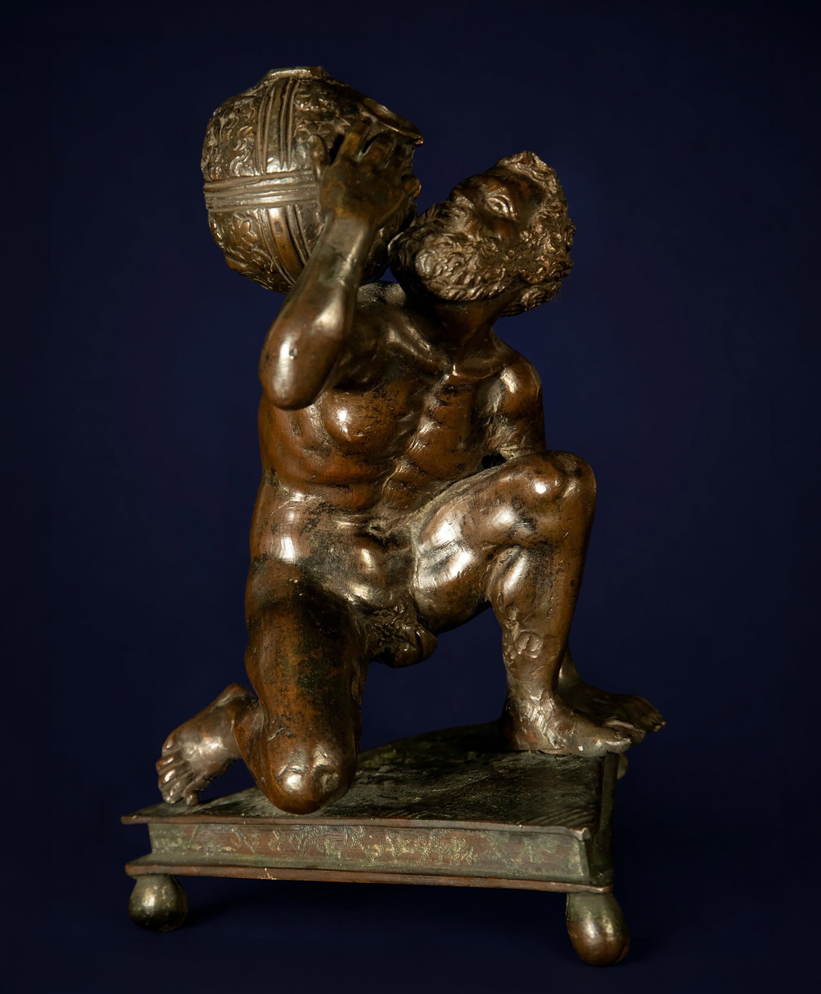 ATTRIBUTED TO ANDREA BRUSTOLON, CALLED “IL RICCIO?? (Padua, 1470 – 1532) - Oil lamp with male: Cast and chased bronze. Dimensions: 16 x 16 x 24 cm. This sculpture depicts a kneeling, nude male figure on a quadrangular base, holding a spherical vessel on his shoulder, originally intended as an o