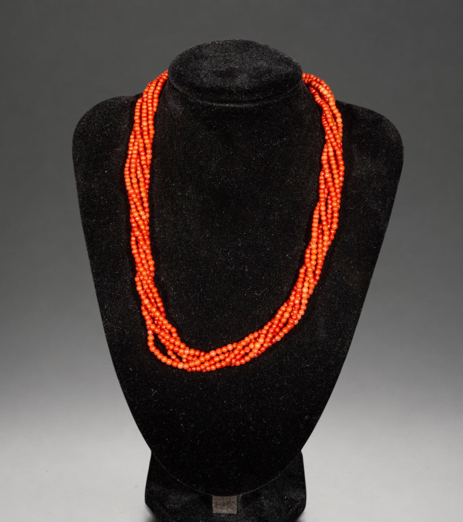 Five-strand coral necklace with 18K gold clasp: This necklace features five strands of small, spherical, deep red natural coral beads, finished with a decorative 18K gold clasp. The arrangement of the multiple strands creates an elegant effect of v